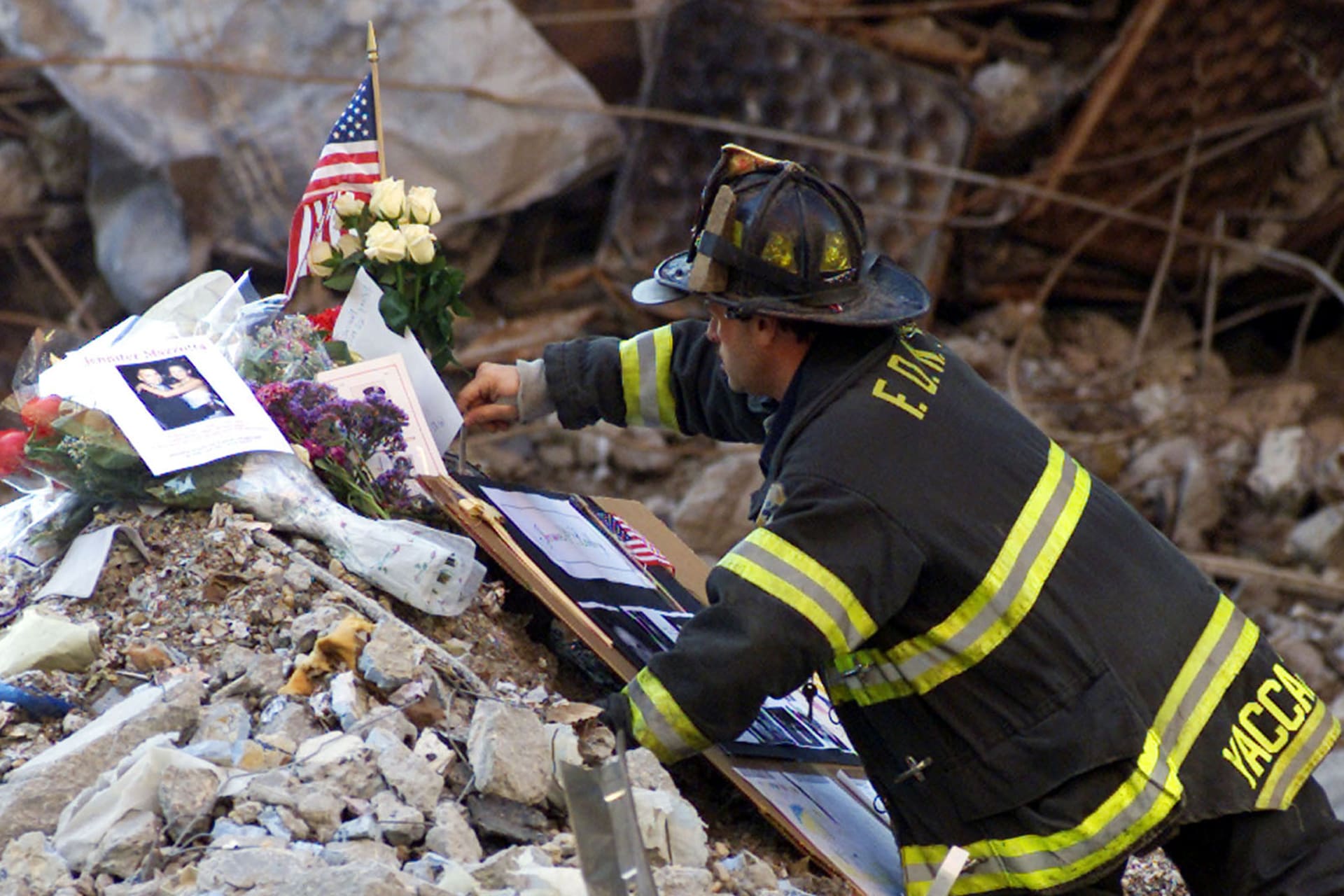 A New York City firefighter places flowers and mementos from family members of the victims of the World Trade Center disaster amidst the wreckage following a memorial service for the victims of the September 11 attack at the site in New York on October 28, 2001.