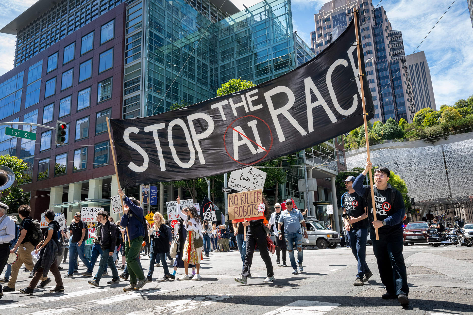 Demonstrators carry a large banner with the words 'Stop the AI race' as they participate in the Stop the AI Race protest march in San Francisco, California, on July 11, 2026. The march included stops outside the offices of OpenAI, Anthropic, and Google DeepMind.
