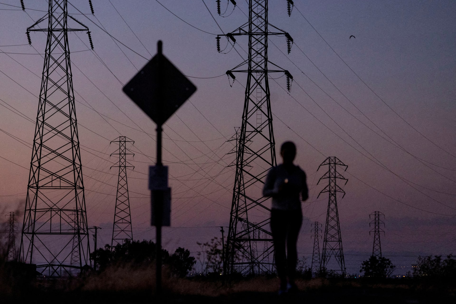 A woman jogs by power lines in California in August 2022.