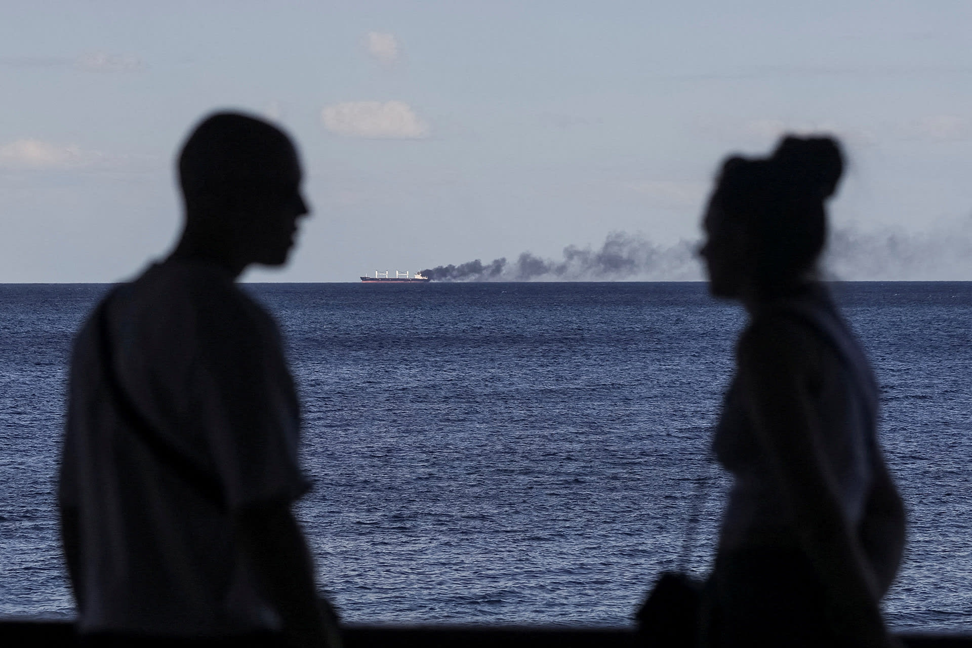 People look on as smoke rises from a civilian vessel on fire, amid Russia's attack on Ukraine, in Odesa, Ukraine, on July 28, 2026.