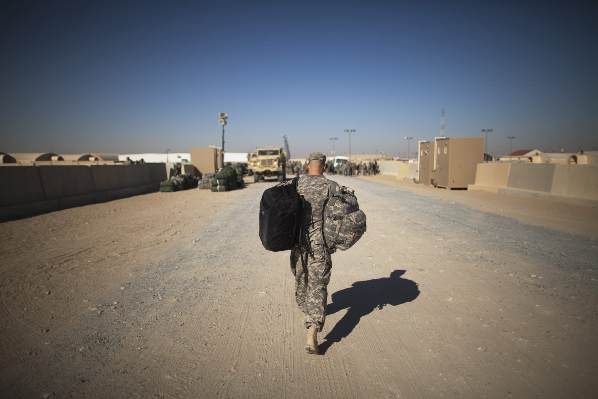A soldier from the 3rd Brigade, 1st Cavalry Division carries his bag to begin his trip back to the United States at Camp Virginia, Kuwait