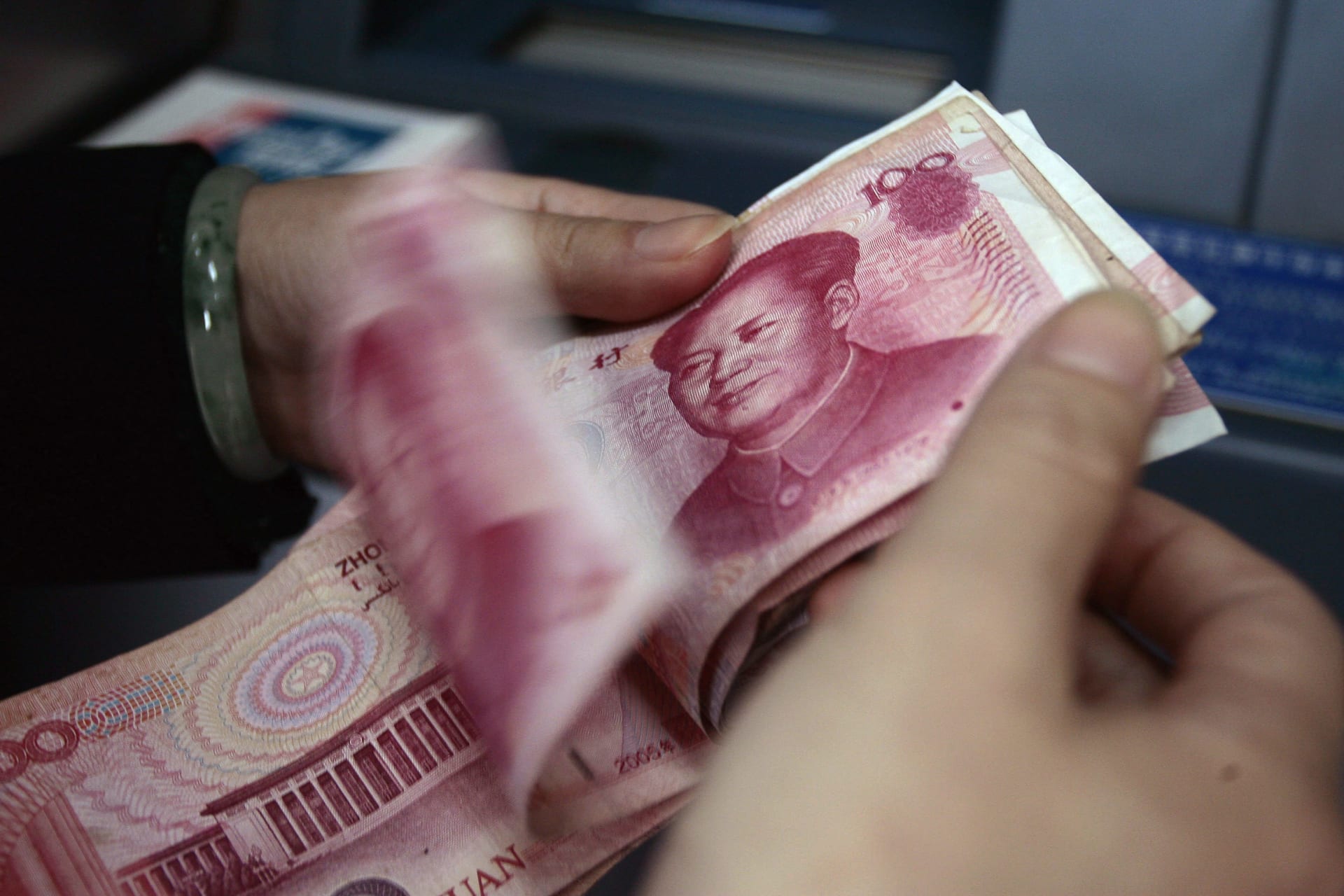 An employee counts Renminbi banknotes at a bank in Nanjing