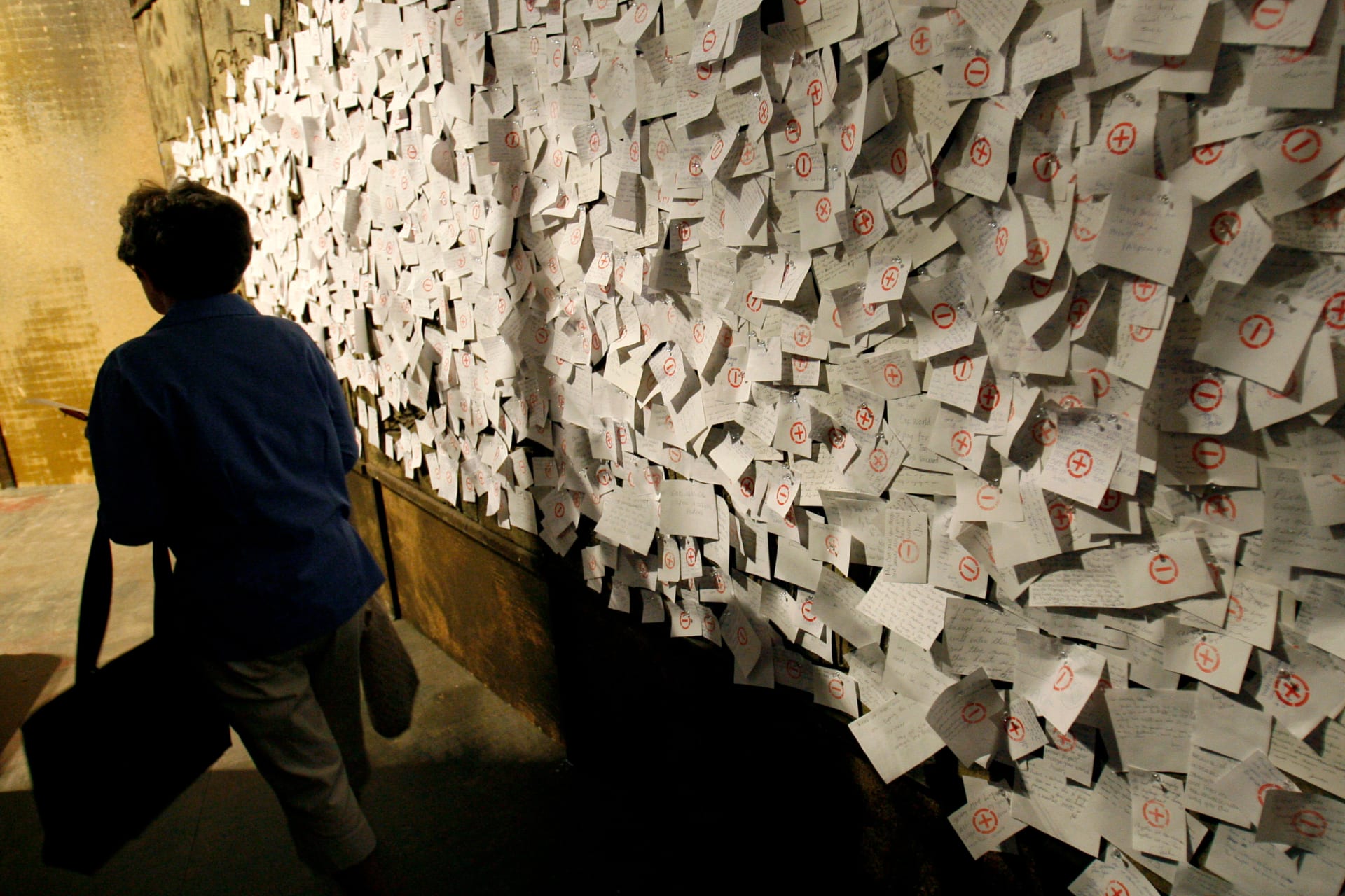 Woman walks past prayer wall where visitors write inspirational messages inside World Vision African AIDS exhibit near site of Sixteenth International AIDS conference in Toronto.