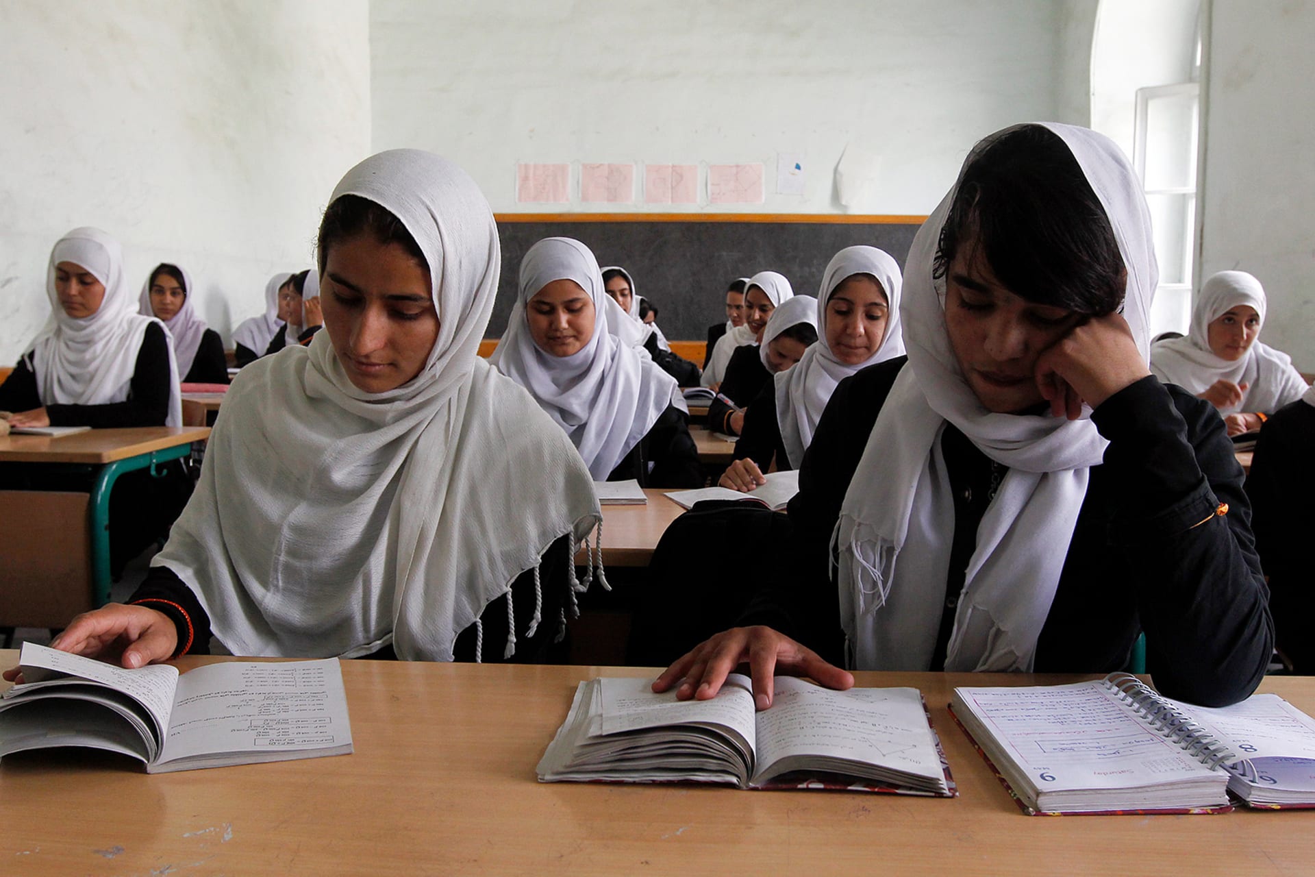 Girls read notes while studying in a school in Kabul.