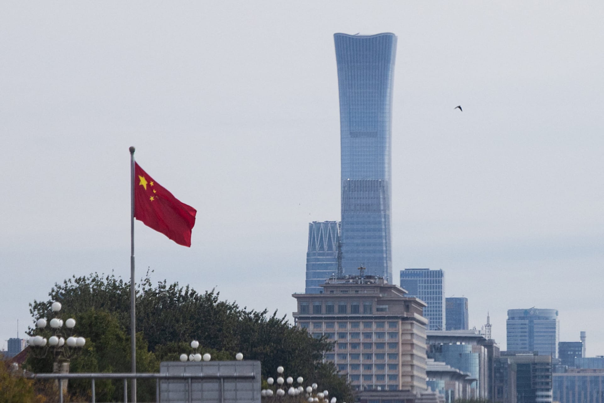 Chinese national flag flies past skyscrapers of the Central Business District as China’s Communist Party leaders open the fifth plenary session of the 20th Central Committee, in Beijing