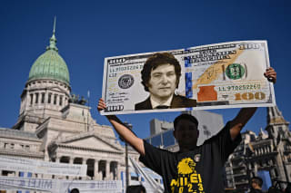 <p>A supporter holds up a $100 bill sign of then President-Elect Javier Milei in December 2023.</p>