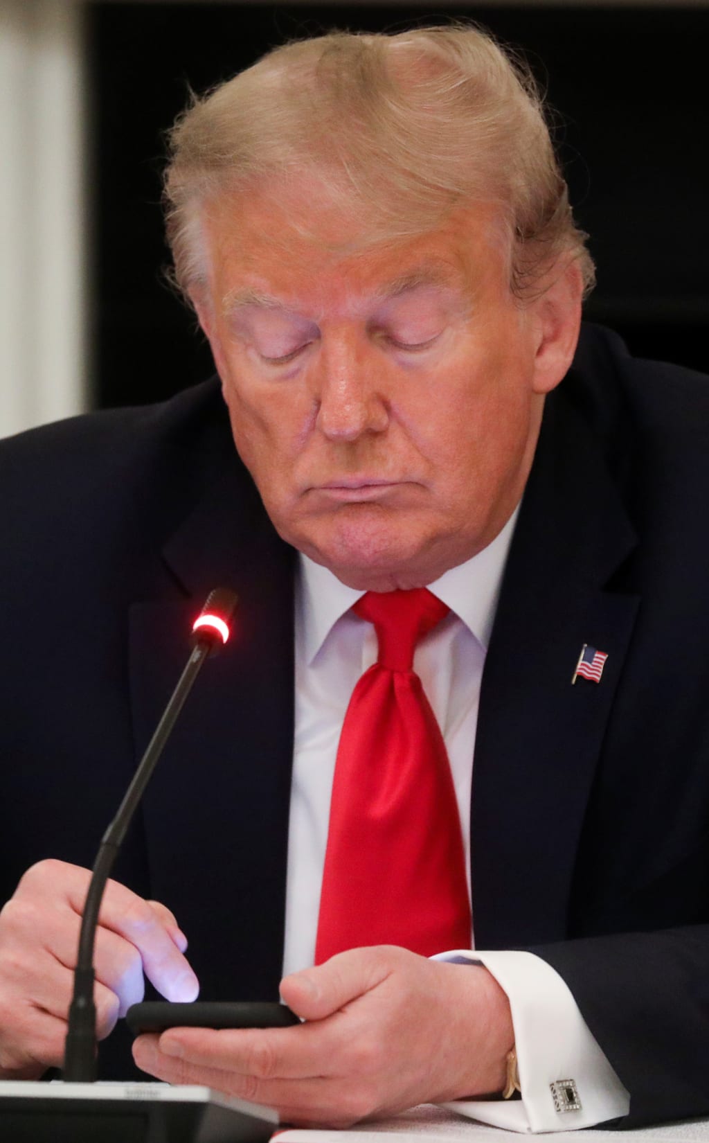 U.S. President Donald Trump taps the screen on a mobile phone at the approximate time a tweet was released from his Twitter account. 