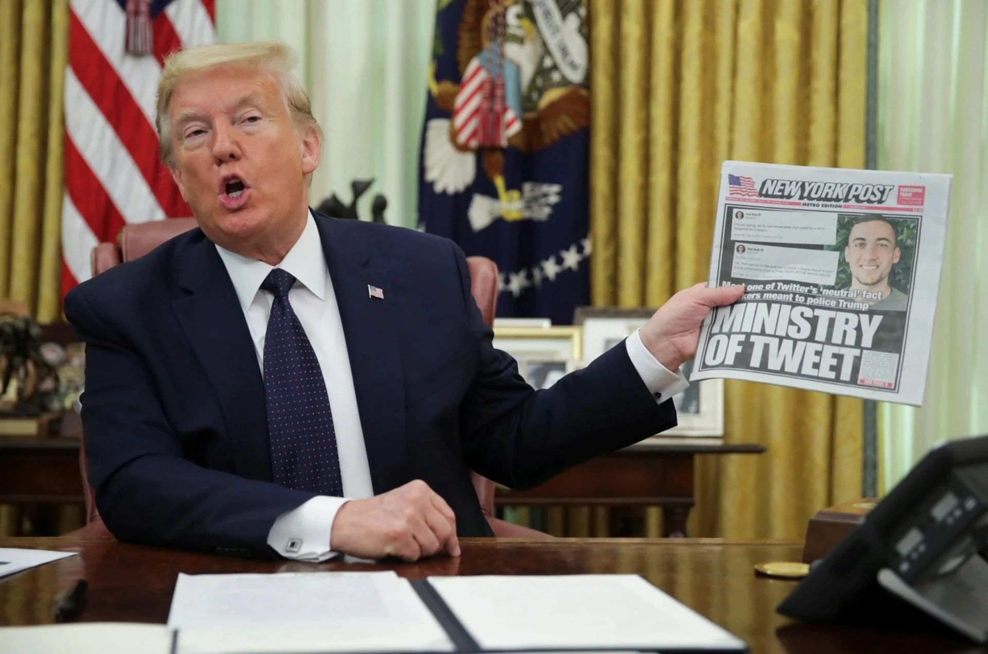 U.S. President Donald Trump holds up a front page of the New York Post. 