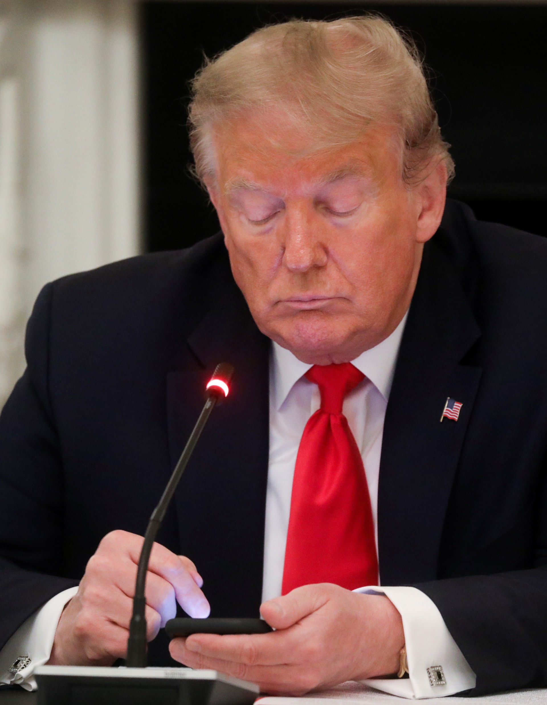 U.S. President Donald Trump taps the screen on a mobile phone at the approximate time a tweet was released from his Twitter account. 