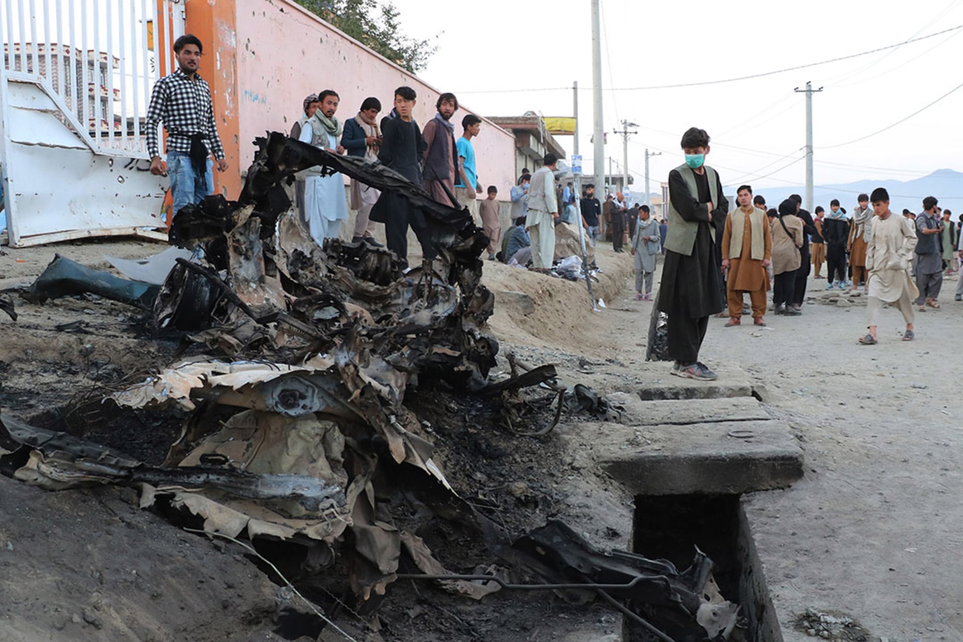 Residents stand outside the Sayed ul-Shuhada school after deadly bombings in May 2021. 
