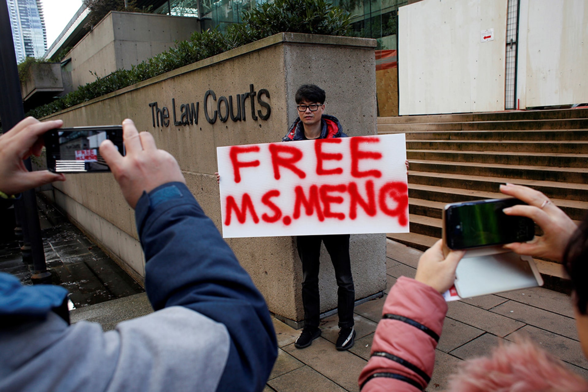 A man holds a sign outside a Canadian court during Meng Wanzhou’s bail hearing. 
