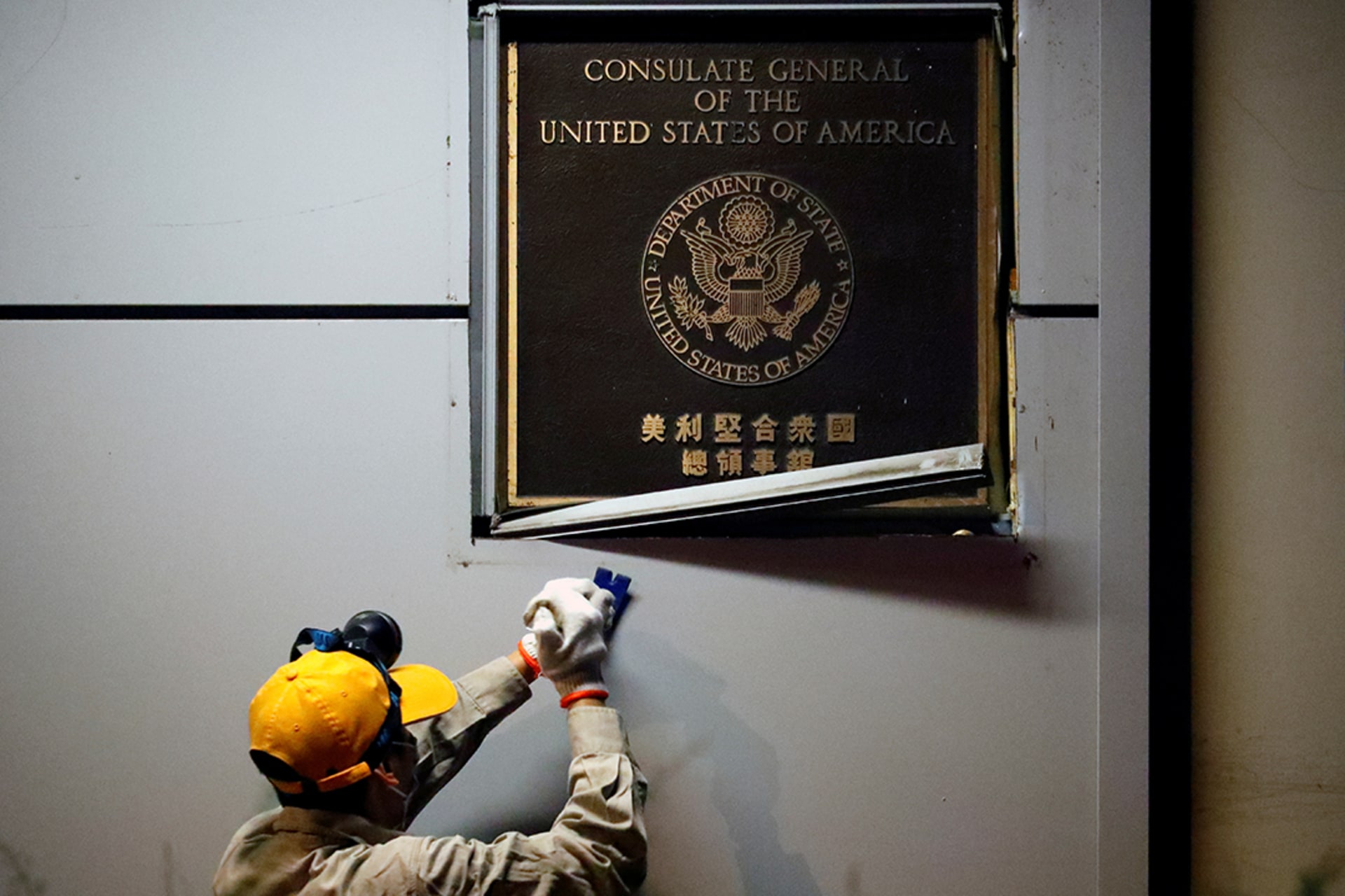 A worker removes a plaque from the U.S. consulate in Chengdu. 
