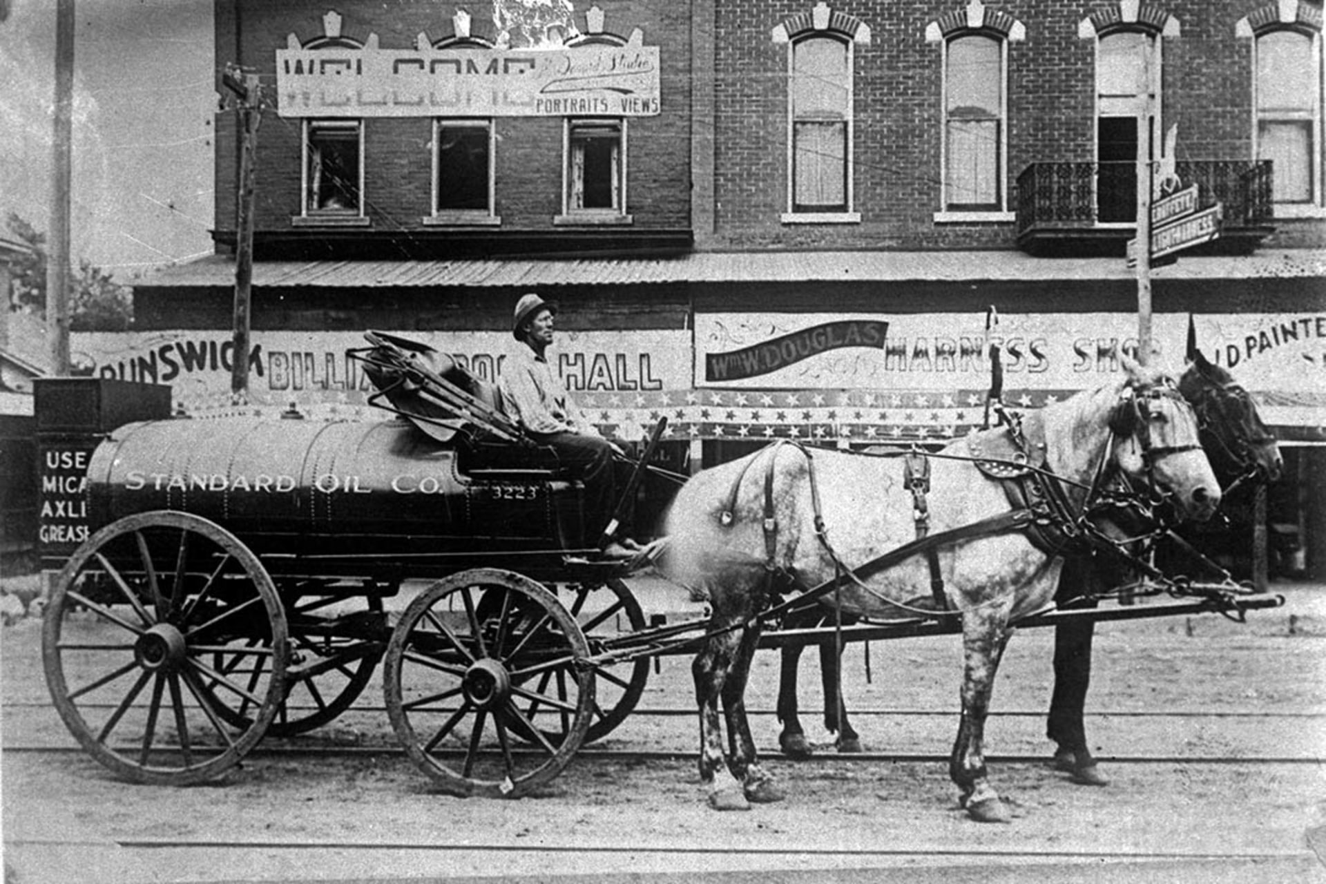 A horse-drawn truck employed by Standard Oil in 1902 delivers gasoline for the first automobiles and stationary engine use. 
