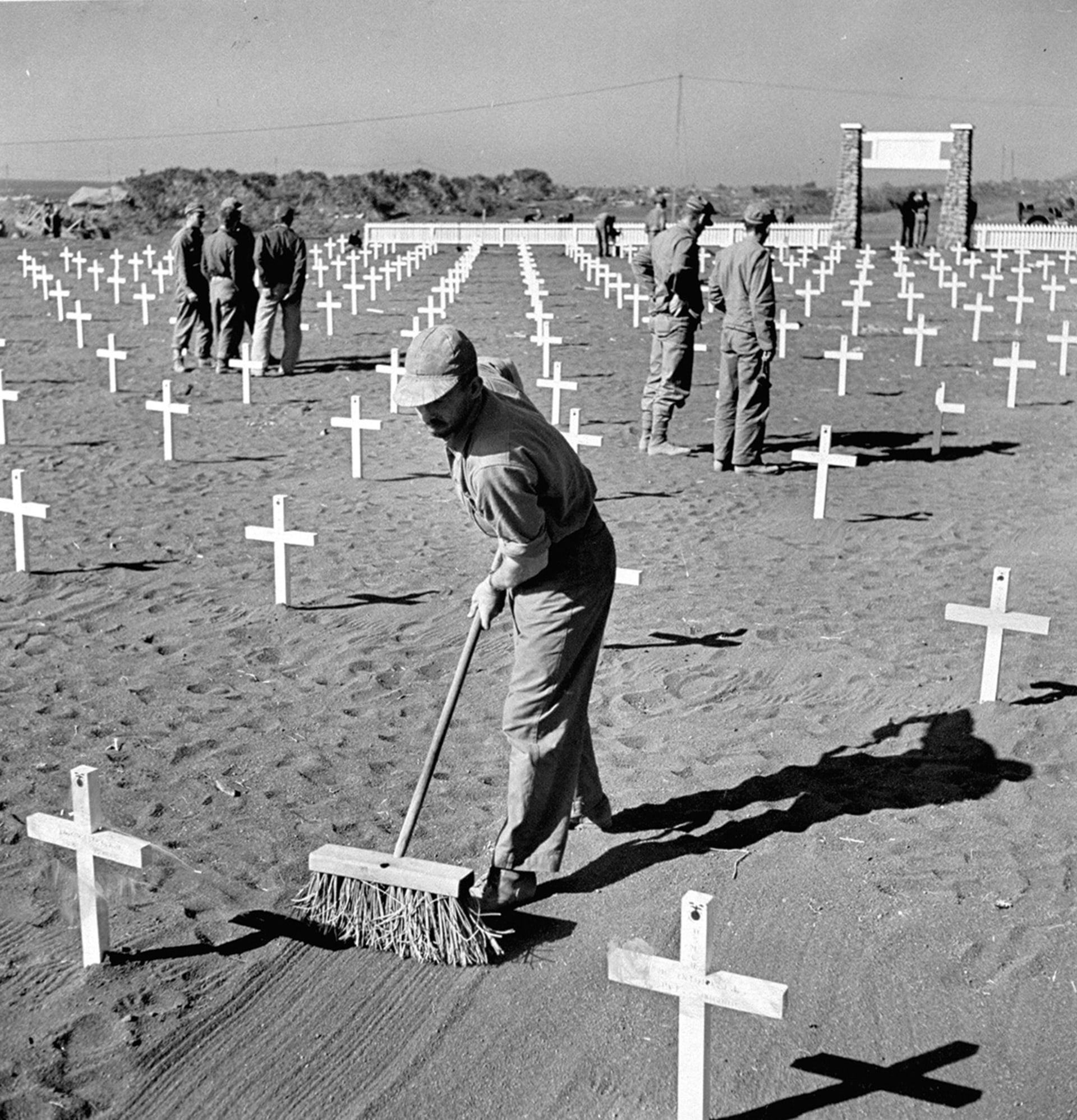 A U.S. Marine smooths the sand at a fifth division cemetery in Iwo Jima after the battle for control of the island.
