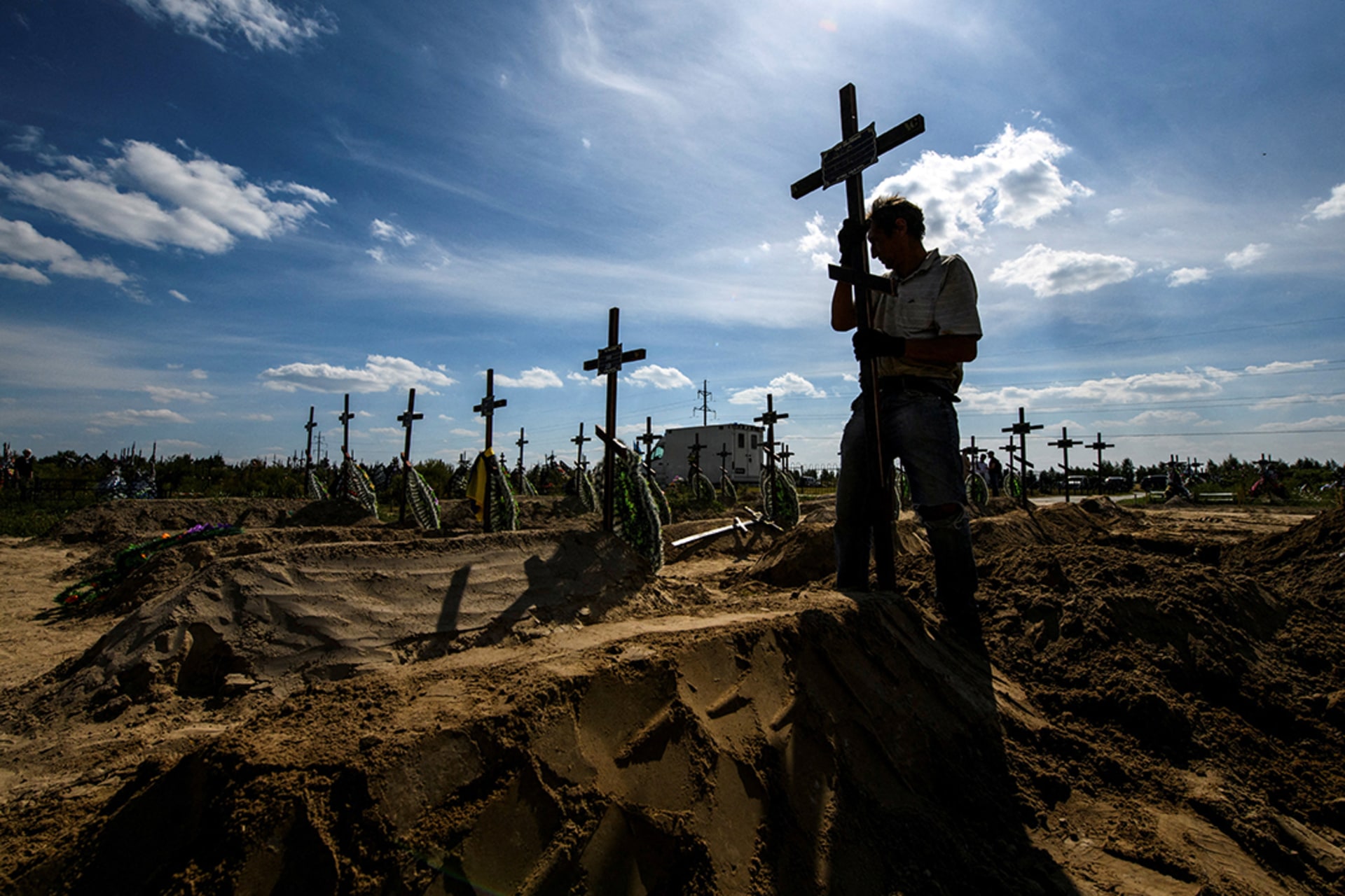 A volunteer places a cross on an unidentified grave of someone killed by Russian forces in Bucha, Ukraine. 
