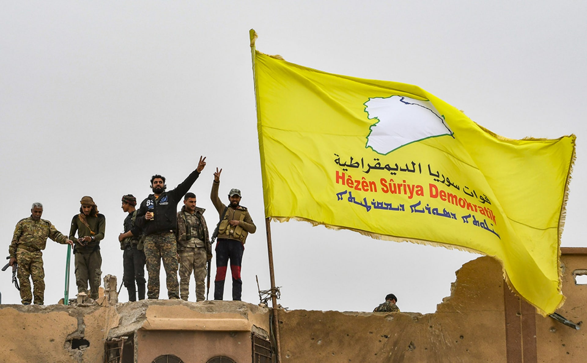 Fighters from the Syrian Democratic Forces (SDF) fly a flag in Baghouz, Syria.