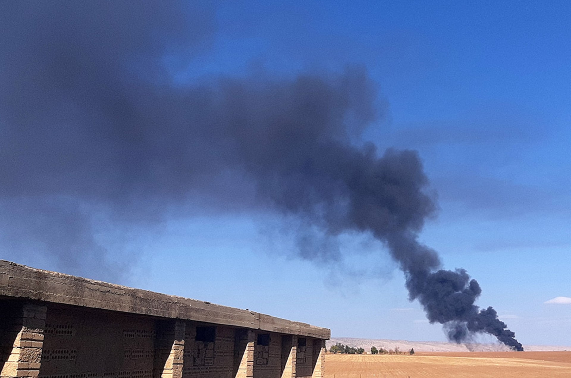 Smoke rises from a field near the Syrian town of al-Qahtaniyah following reports of Turkish drone strikes in the area.