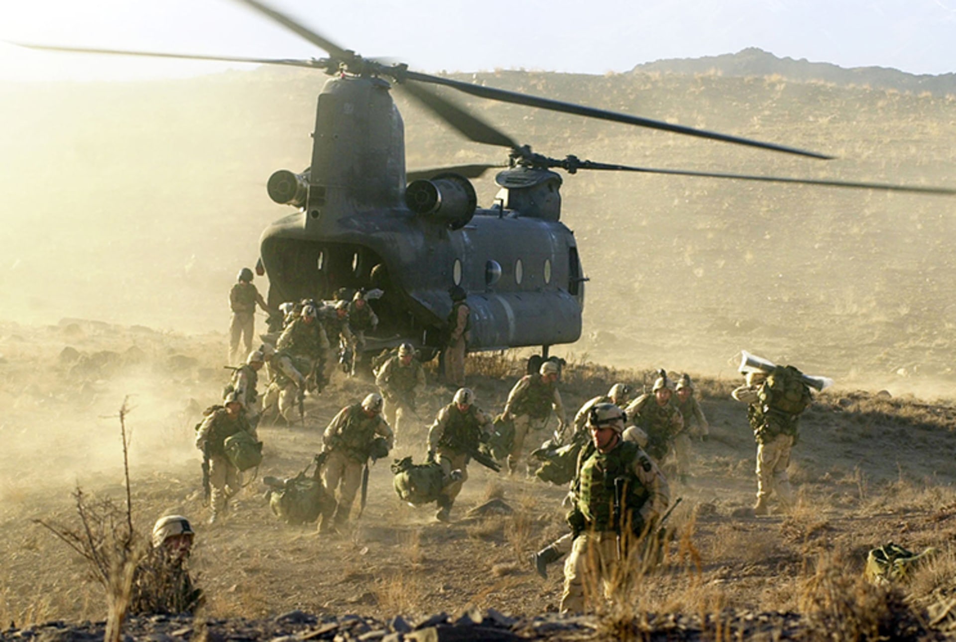 A photo of U.S. soldiers exiting a helicopter in the dessert landscape of Afghanistan.