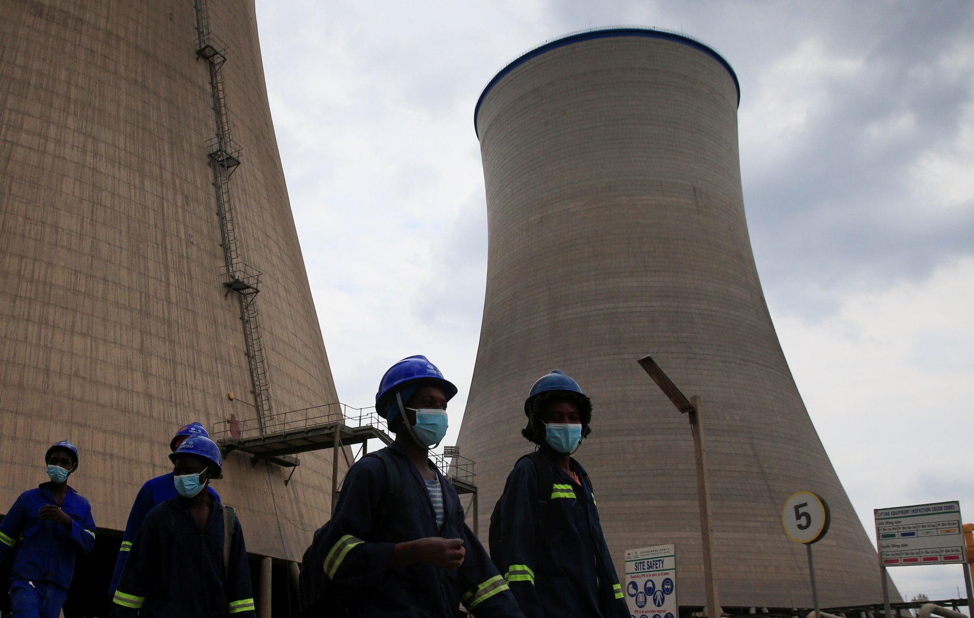 Workers walk beneath cooling towers at Hwange Power station's Phase 8, currently under construction, in Hwange, Zimbabwe, on October 19, 2021.