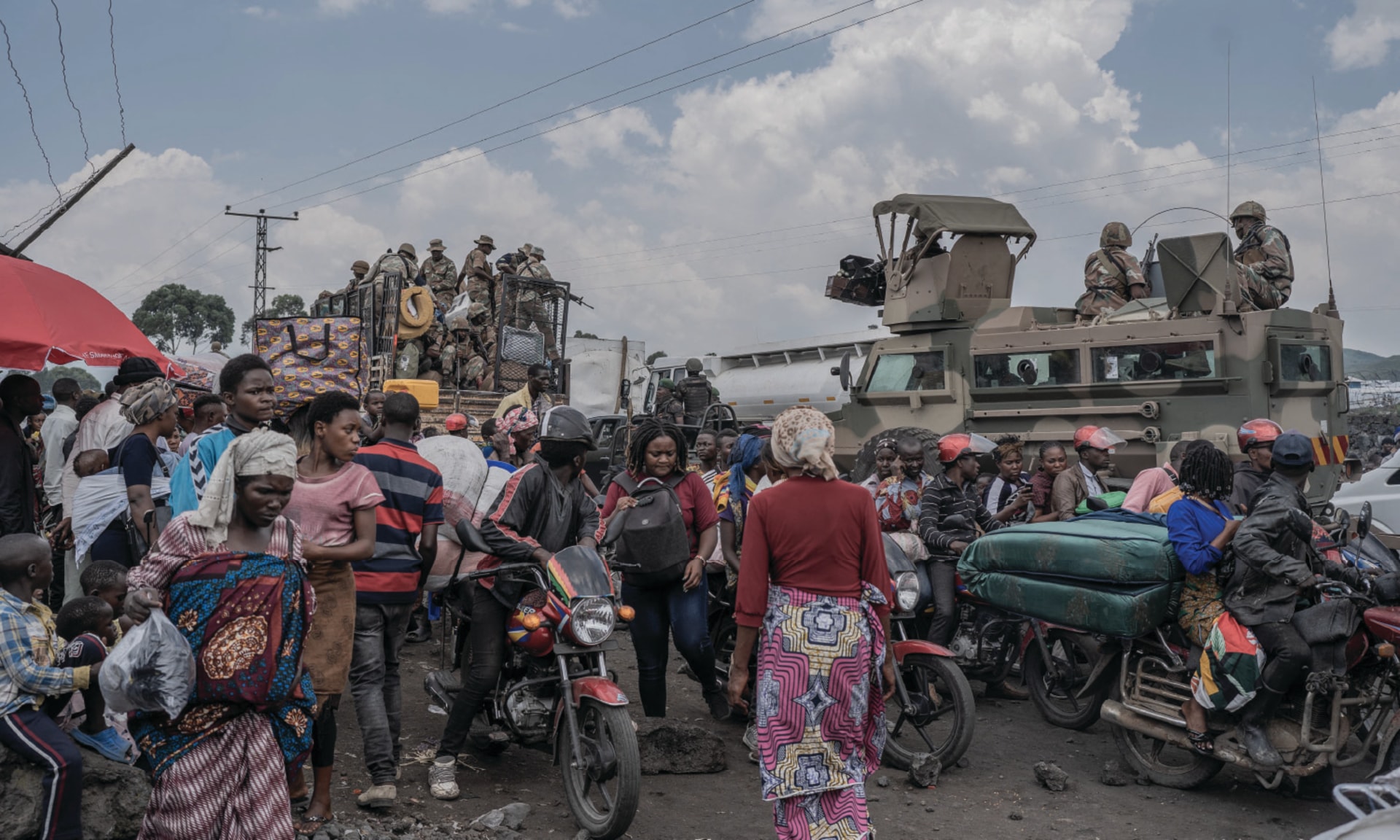 People gather near Southern African Development Community Mission vehicles while fleeing rebel-government clashes in Sake, Democratic Republic of the Congo.