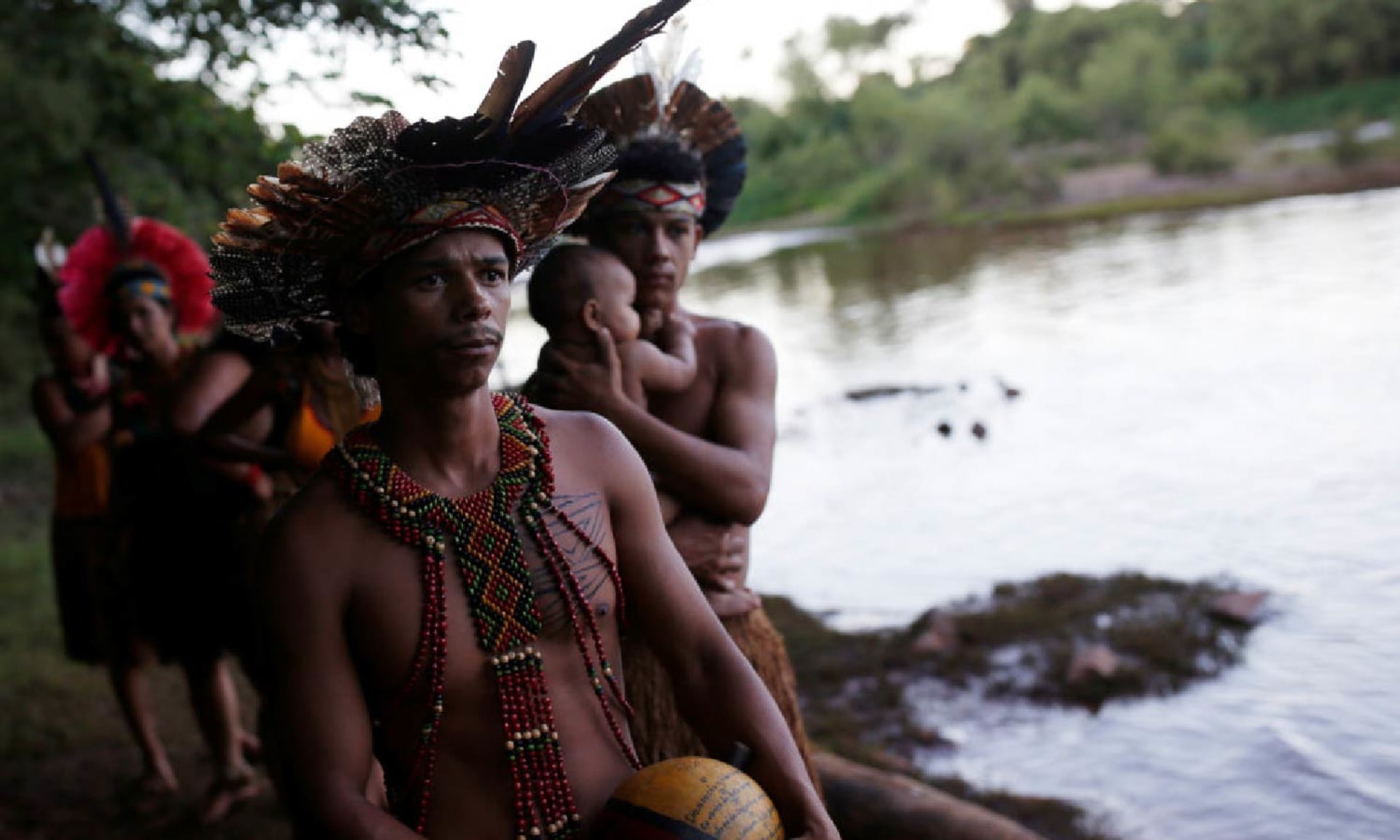 Members of the Brazilian Pataxo Ha-ha-hae tribe stand by a river.