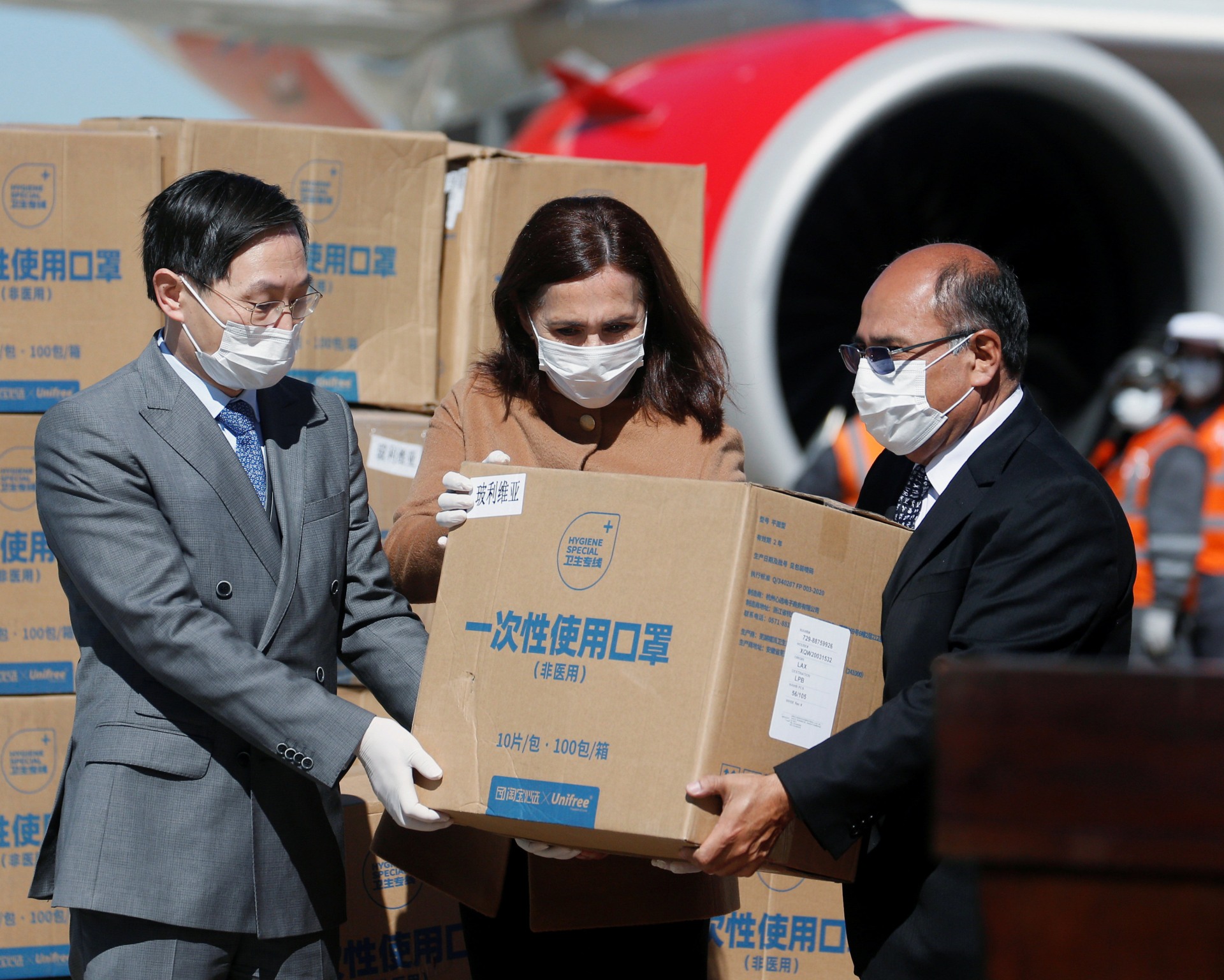 Three people receive boxes of covid-19 mask donations made to China amidst the pandemic in 2020.