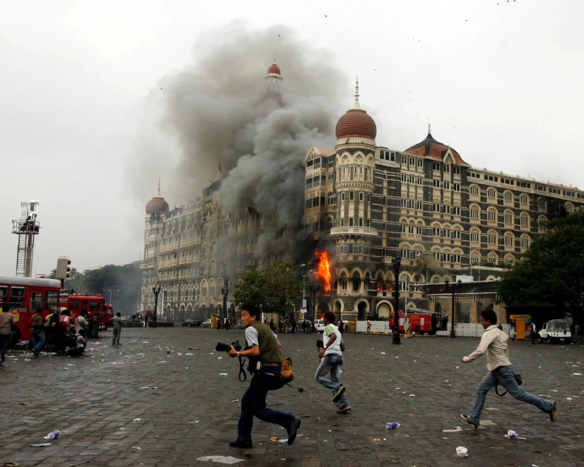 Flames emerge from a building as photographers run past the Taj Mahal Hotel in Mumbai, India, on November 29, 2008. The hotel was one of the sites targeted during a coordinated terror attack on the city.