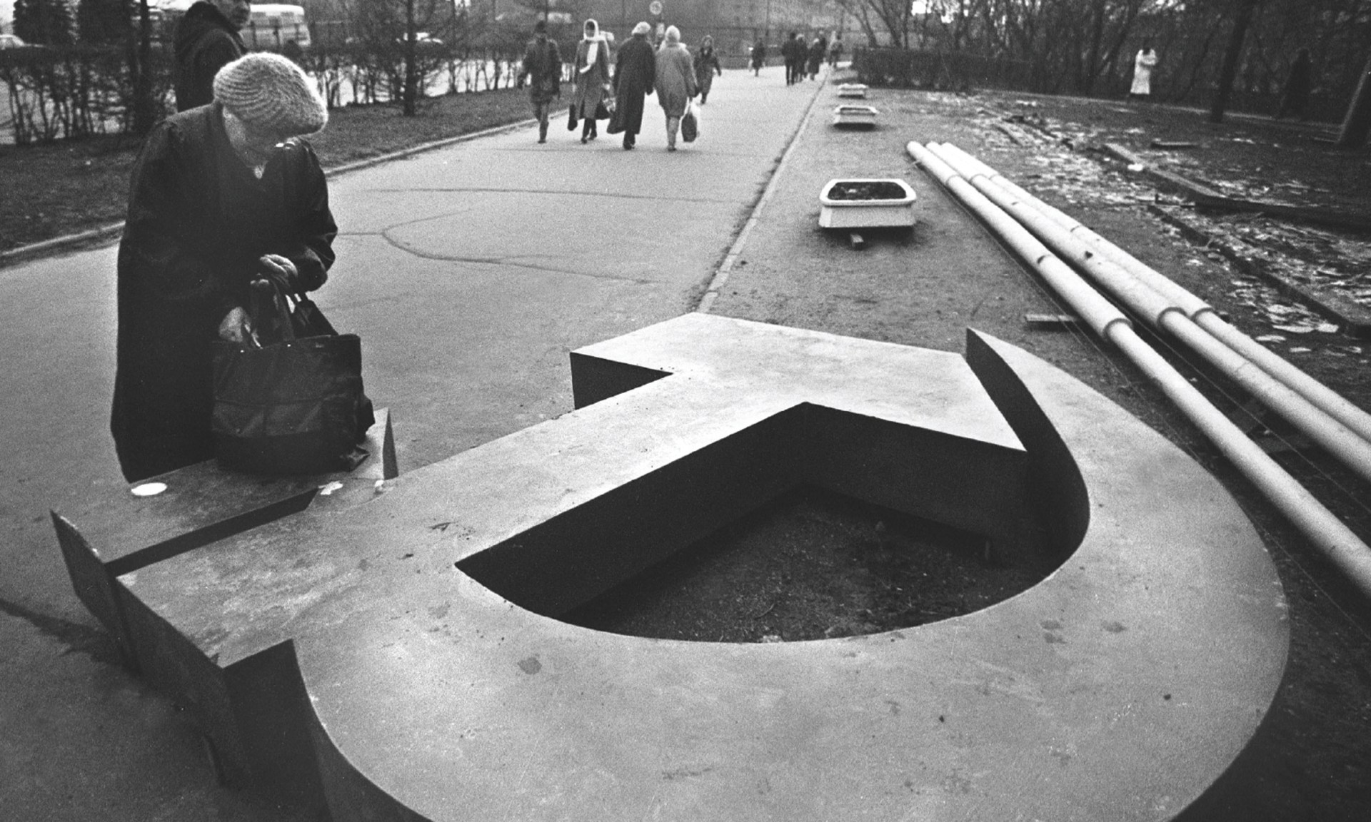 A woman reaches into her bag, which rests on a fallen Soviet hammer-and-sickle on a Moscow street in November, 1991.