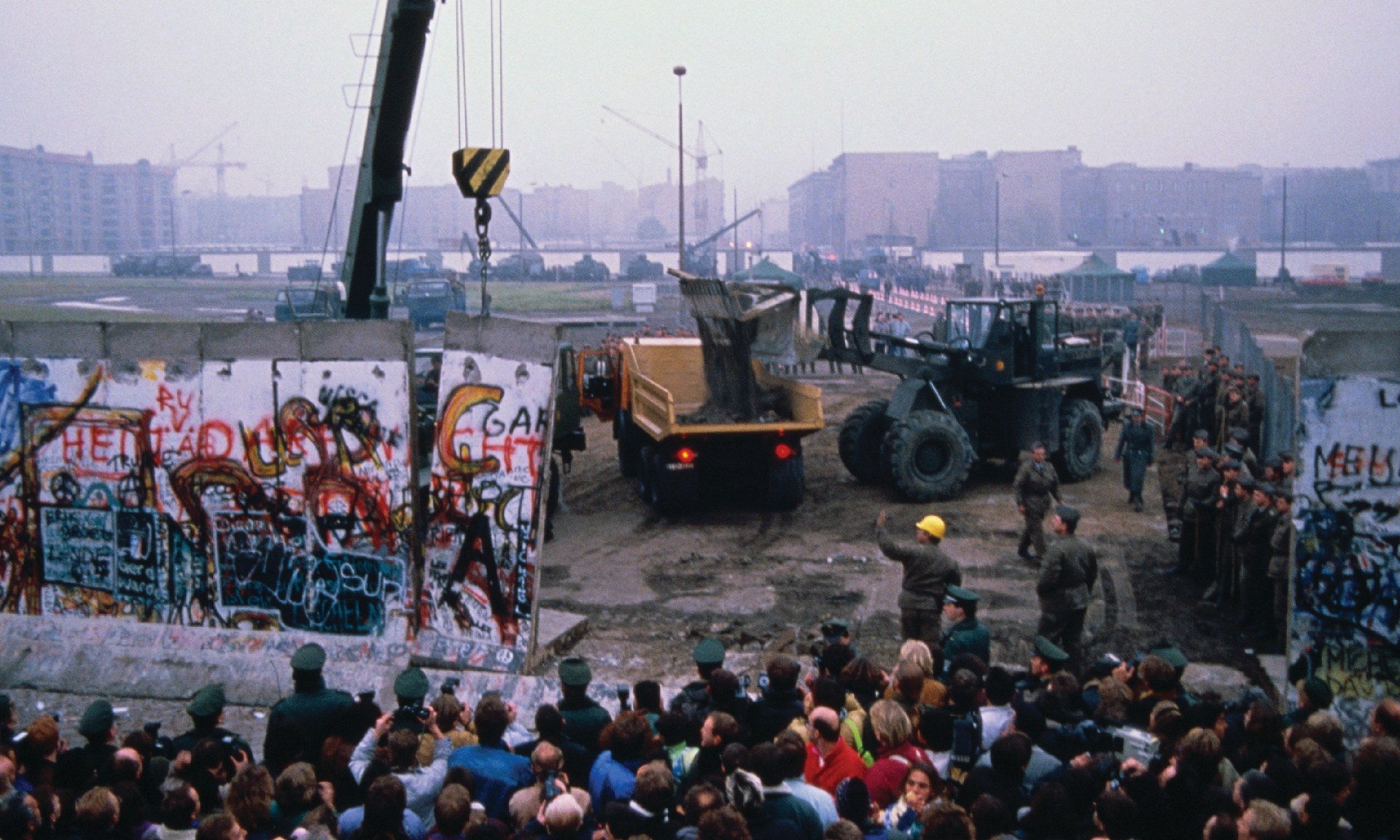 Crowd watches as workmen deconstruct the Berlin Wall in Germany in late 1989.
