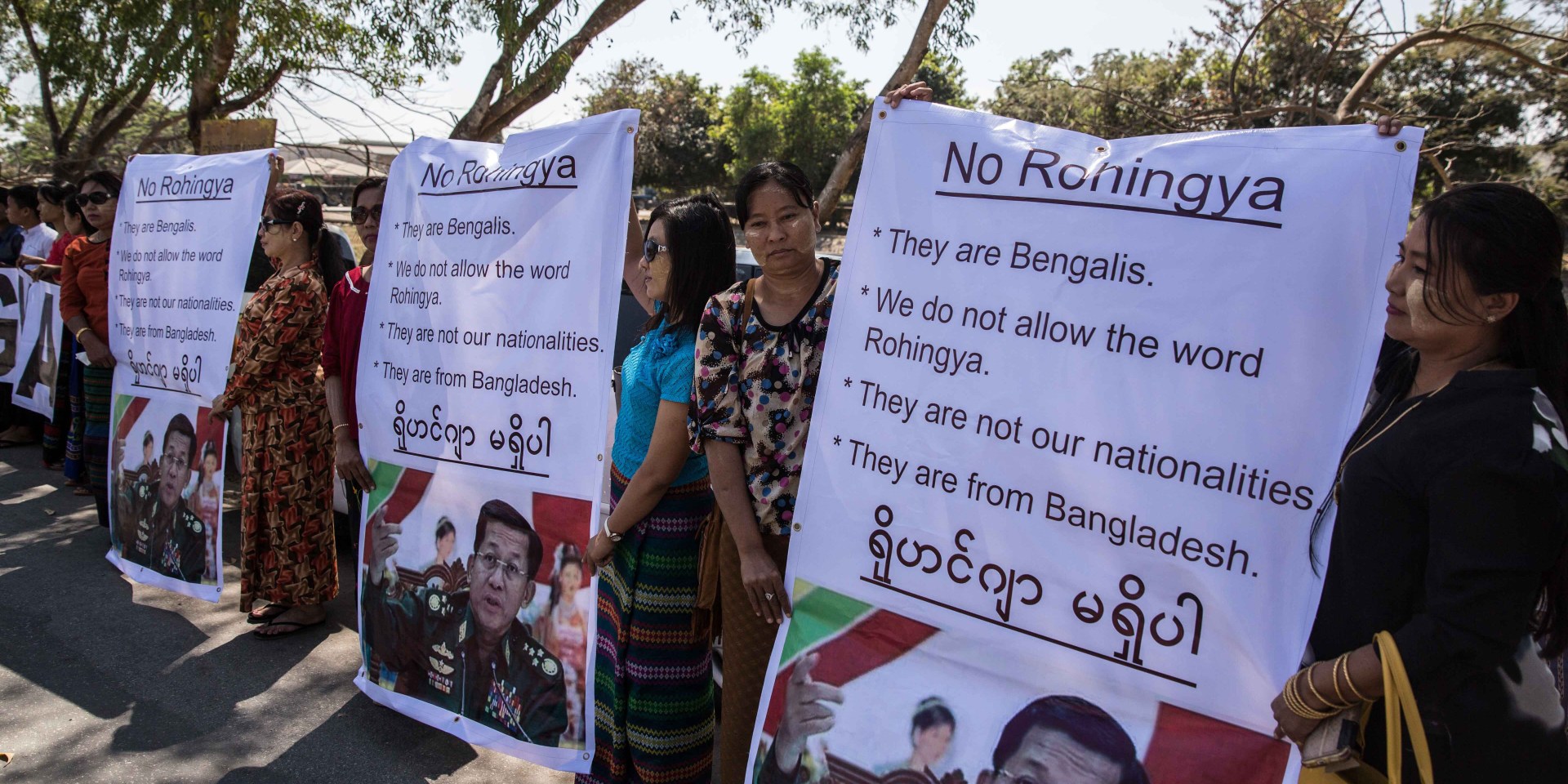 Protesters hold signs objecting to the word ”Rohingya” as an aid ship headed for Rohingya refugee camps docks in Myanmar in 2017.