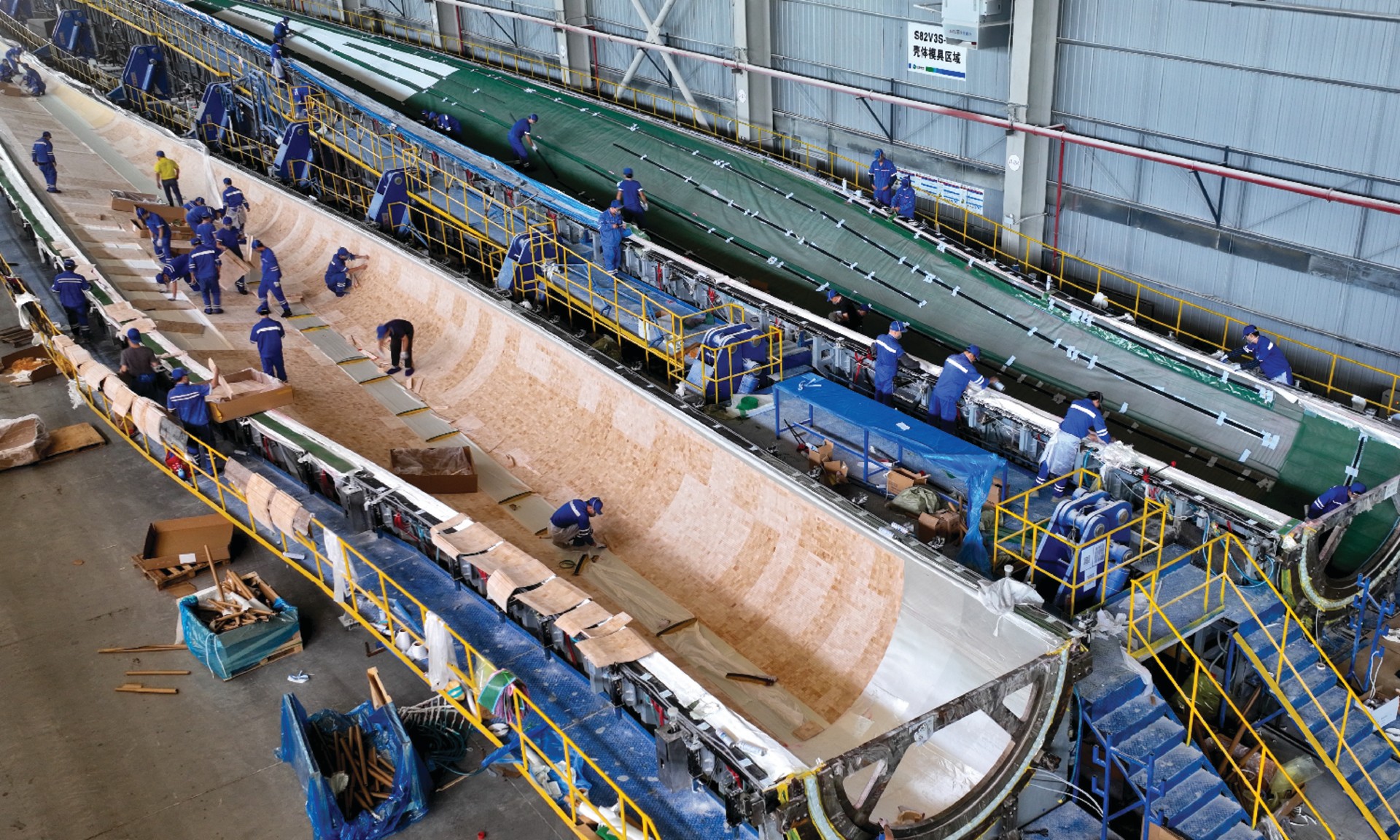 Workers manufacture huge wind turbine blades at a production facility in China