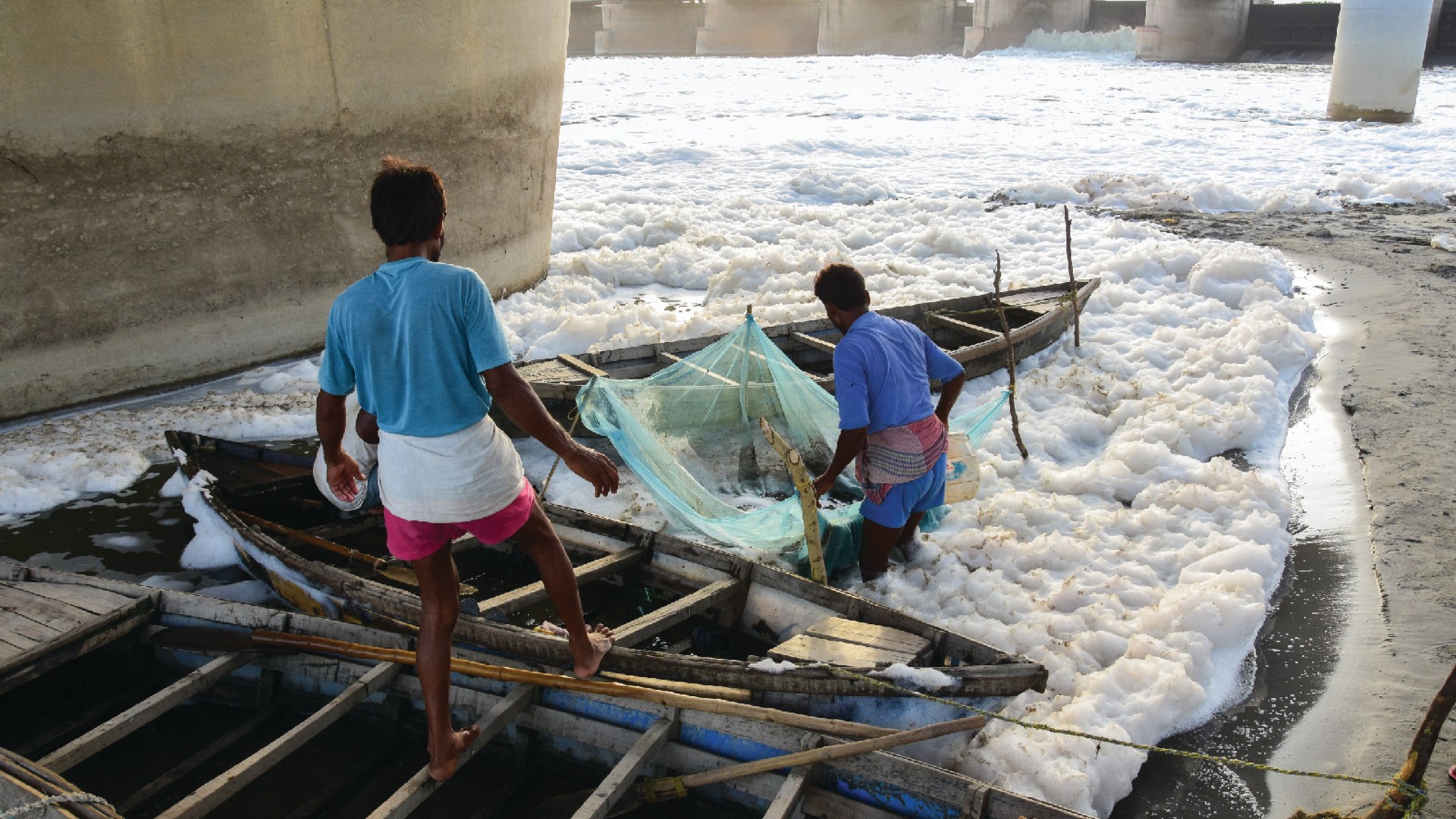 Fishermen work in the heavily polluted waters of the Yamuna River, which are covered with a layer of toxic foam, in New Delhi, India.