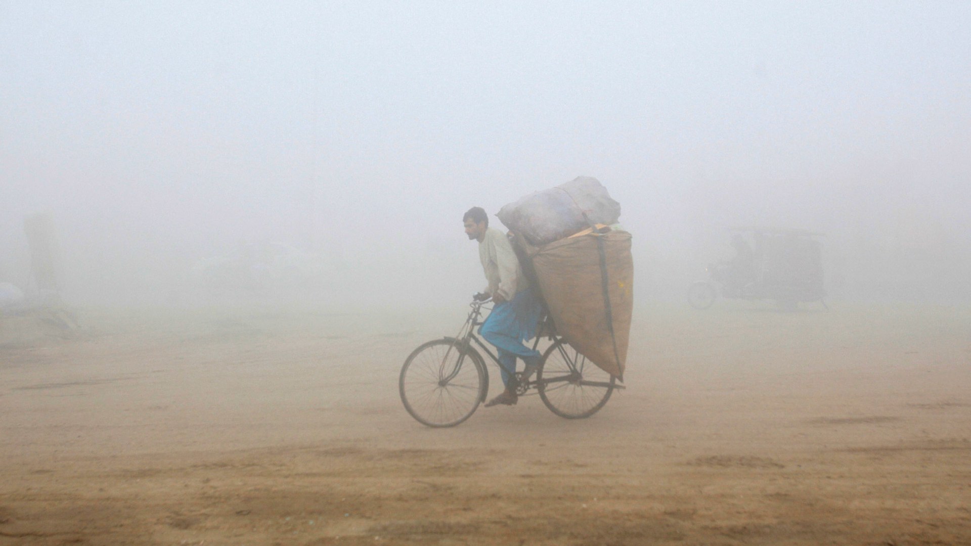 A man rides his bicycle through smog in Lahore, Pakistan on November 20, 2017.