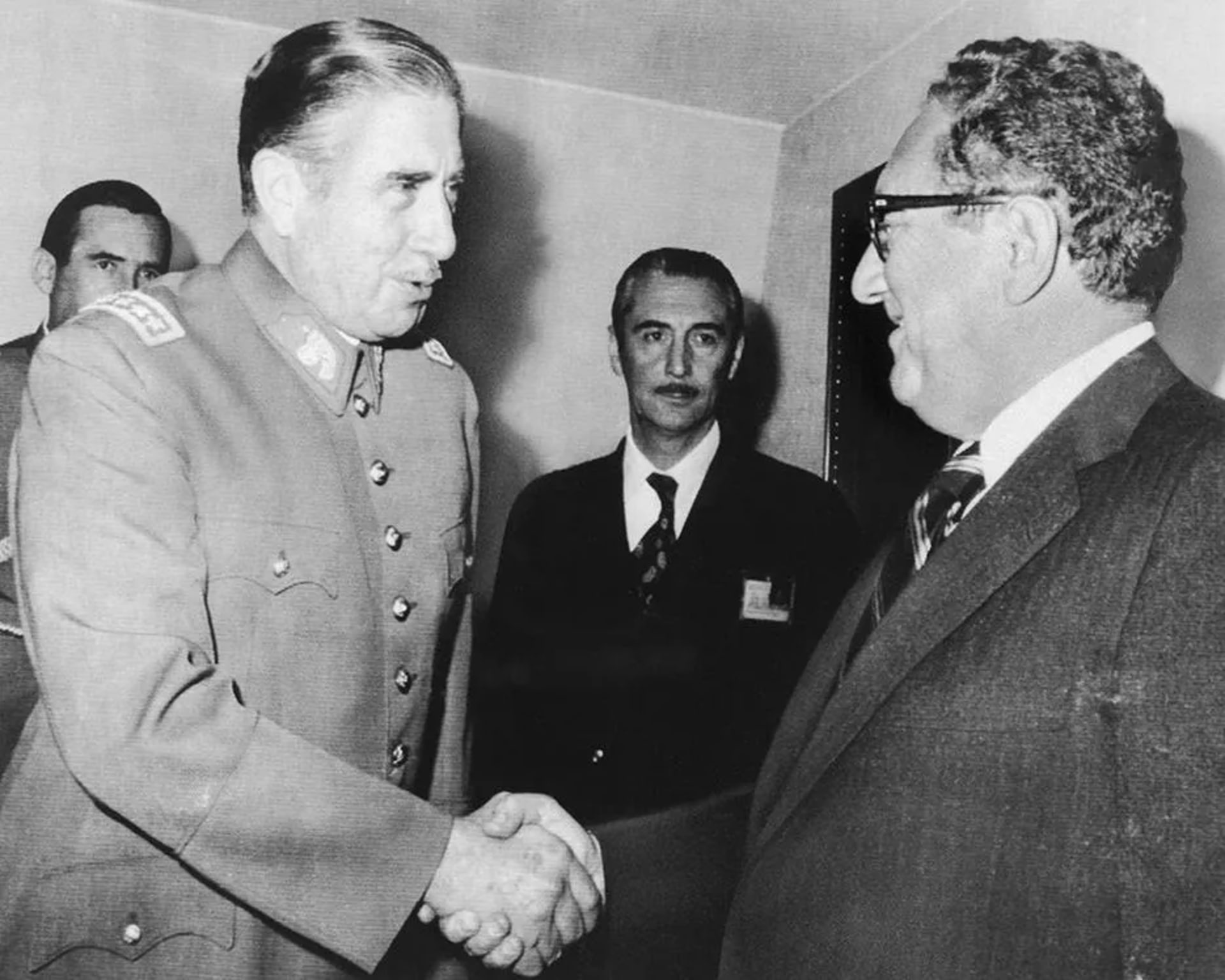 Chilean President Augusto Pinochet (left) shakes U.S. Secretary of State Harry Kissinger's (right) hand.