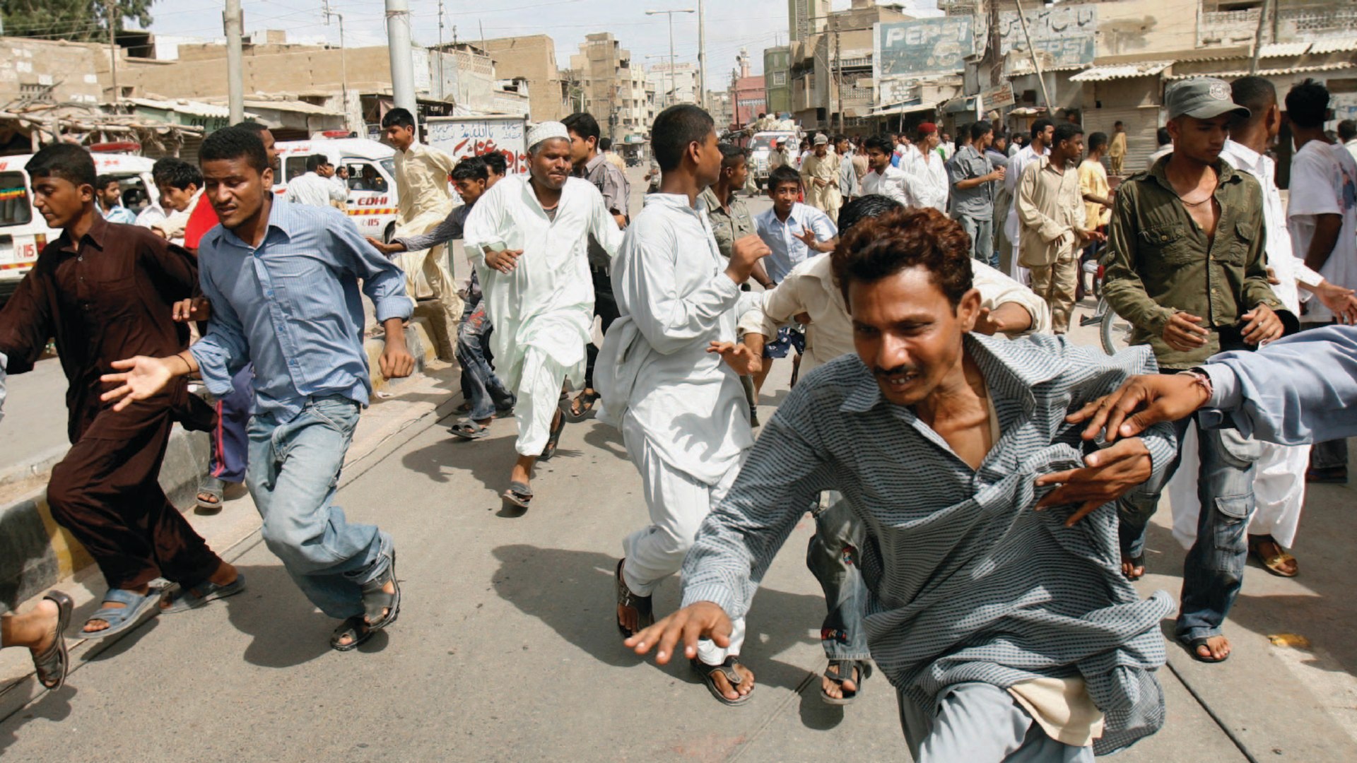 People flee from gunfire during a firefight between rival gangs in Karachi, Pakistan
