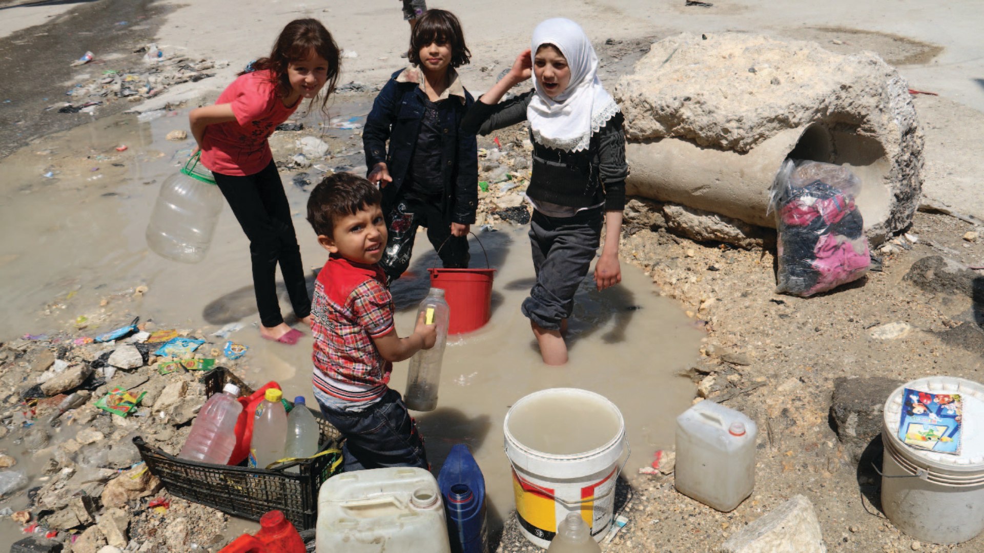 Children in a rebel-held area of Aleppo, Syria, collect stagnant, murky water on May 12, 2014. Residents had been without water for over a week as jihadists have cut supplies to both rebel and regime-held areas.
