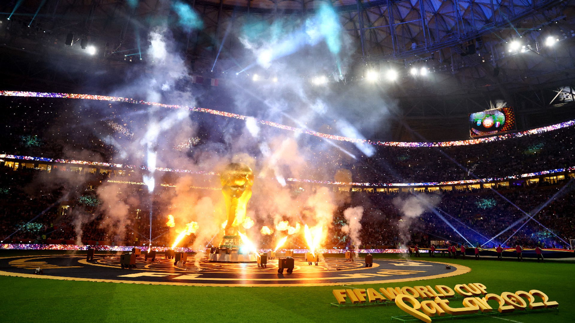 The FIFA World Cup 2022 closing ceremony held in Lusail Stadium, Lusail, Qatar can be seen as a giant FIFA trophy stands in the center and celebratory flames surround it.