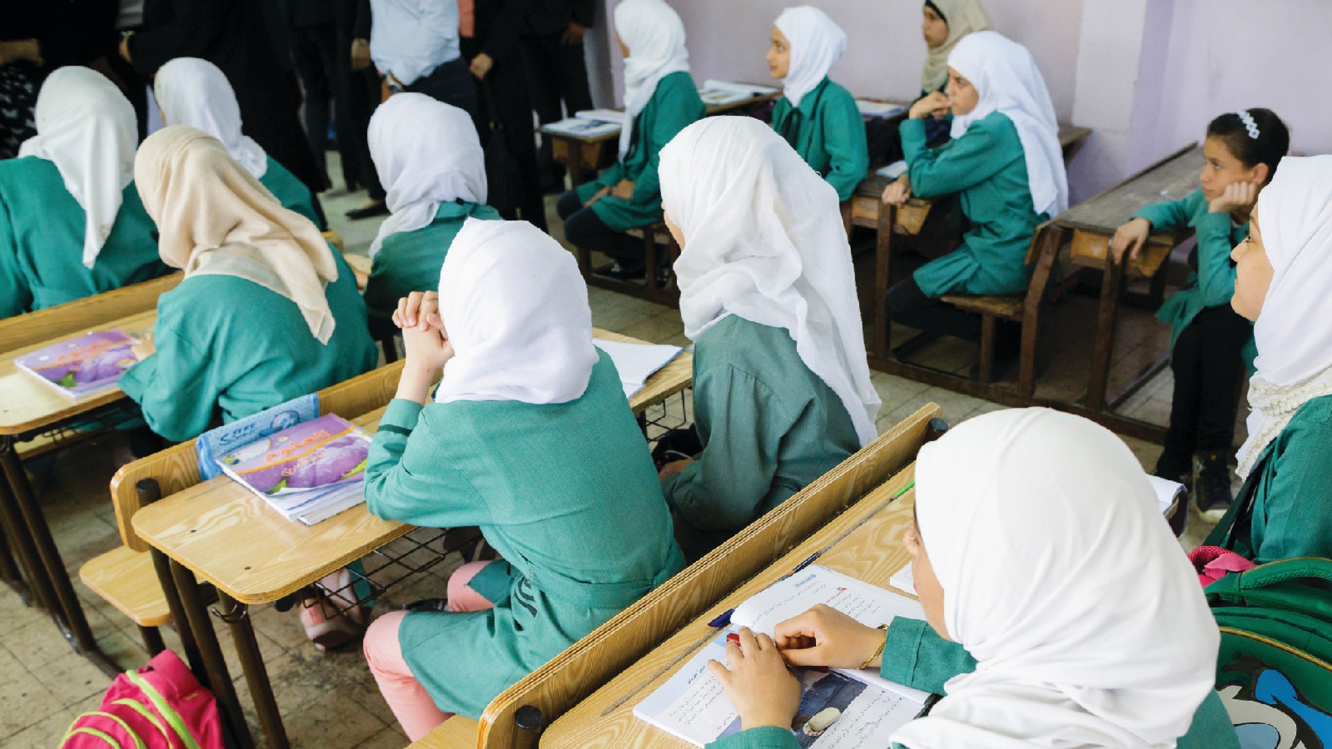 Girls are sitting on school benches during a lesson in the Ajnadayn girls school in Irbid, Jordan.