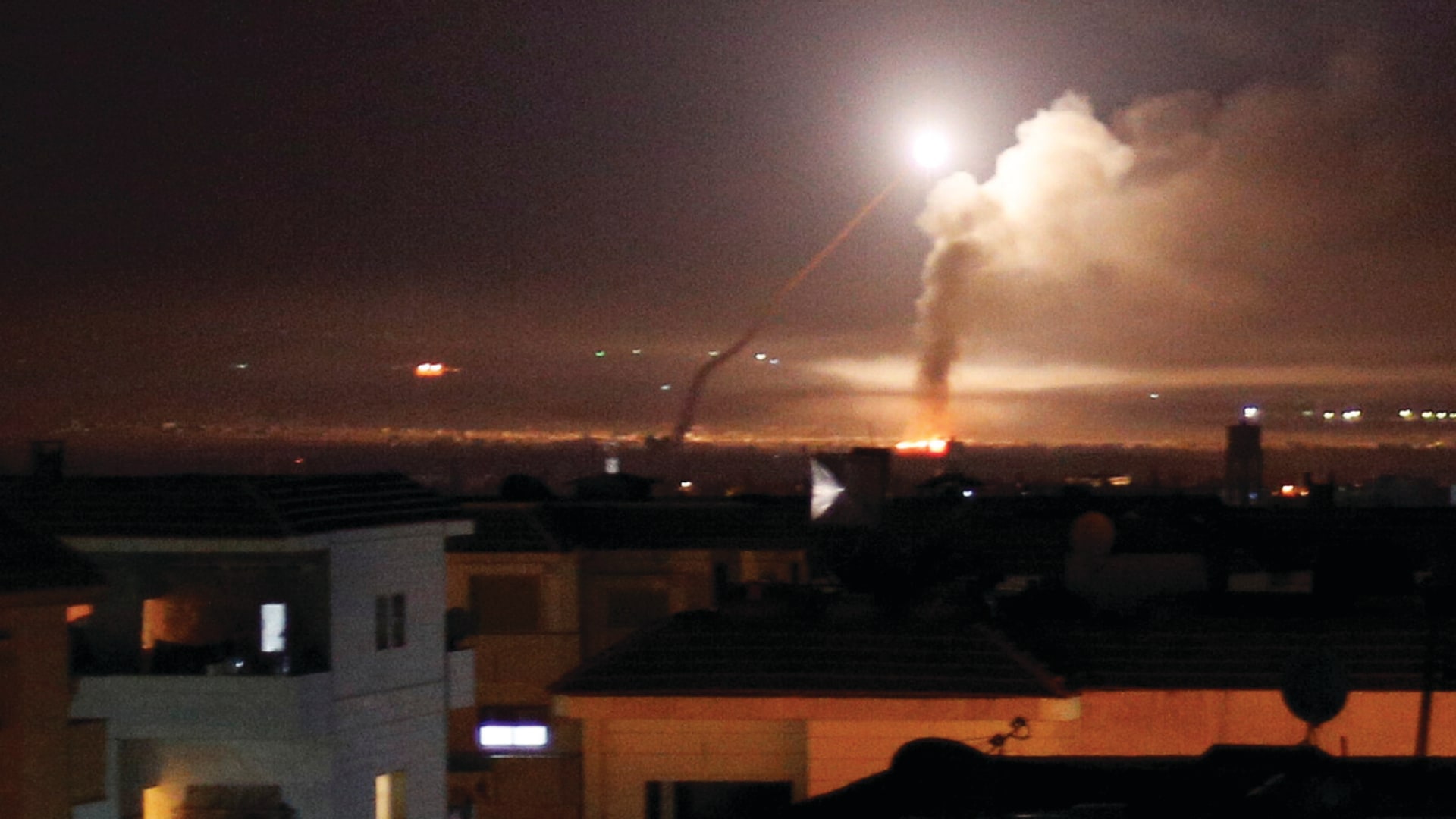 Missile fire is seen from Damascus, Syria as it lights up the sky and a plume of smoke rises.
