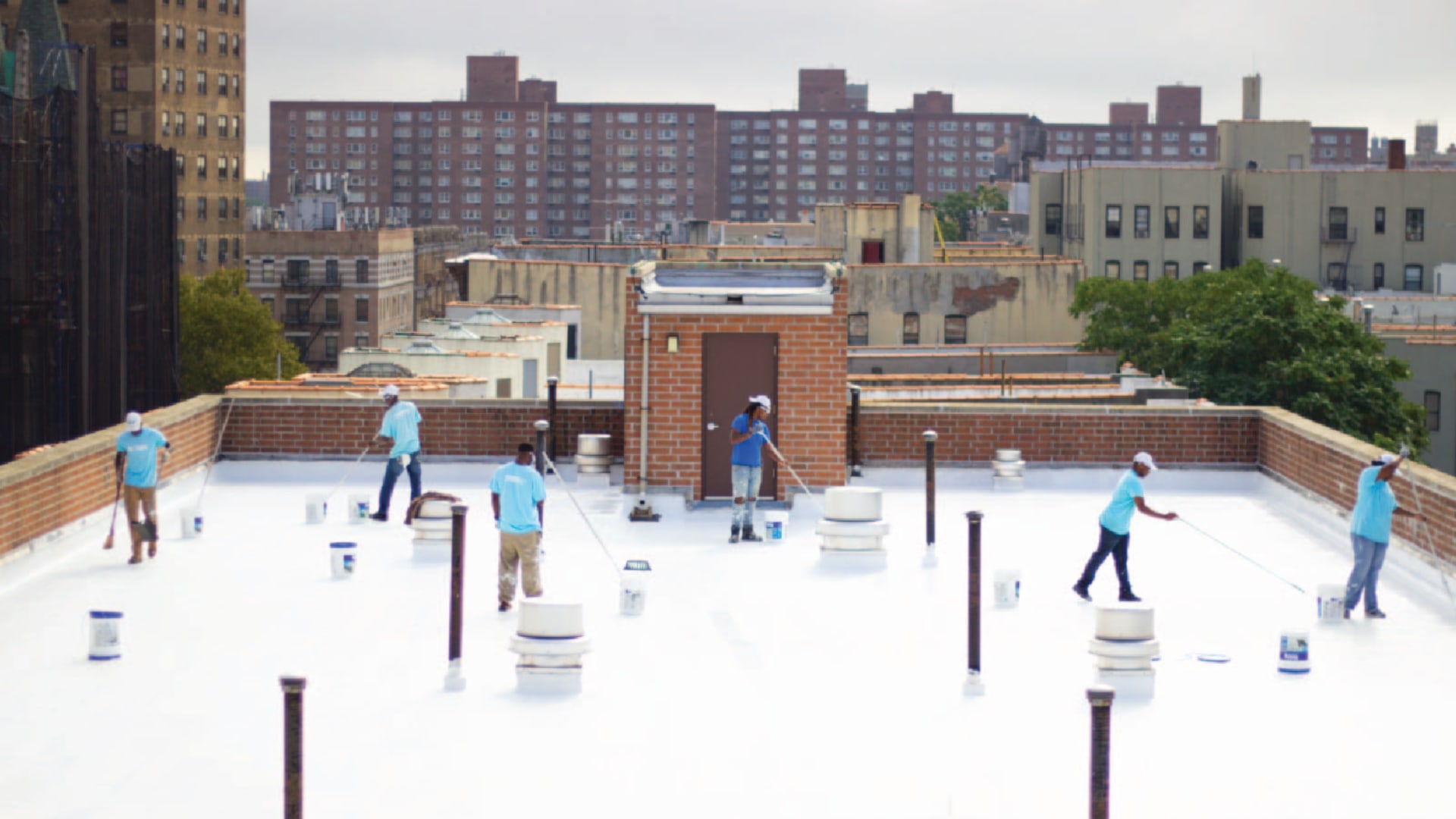 NYC CoolRoofs trainees coat a rooftop with white reflective paint. 