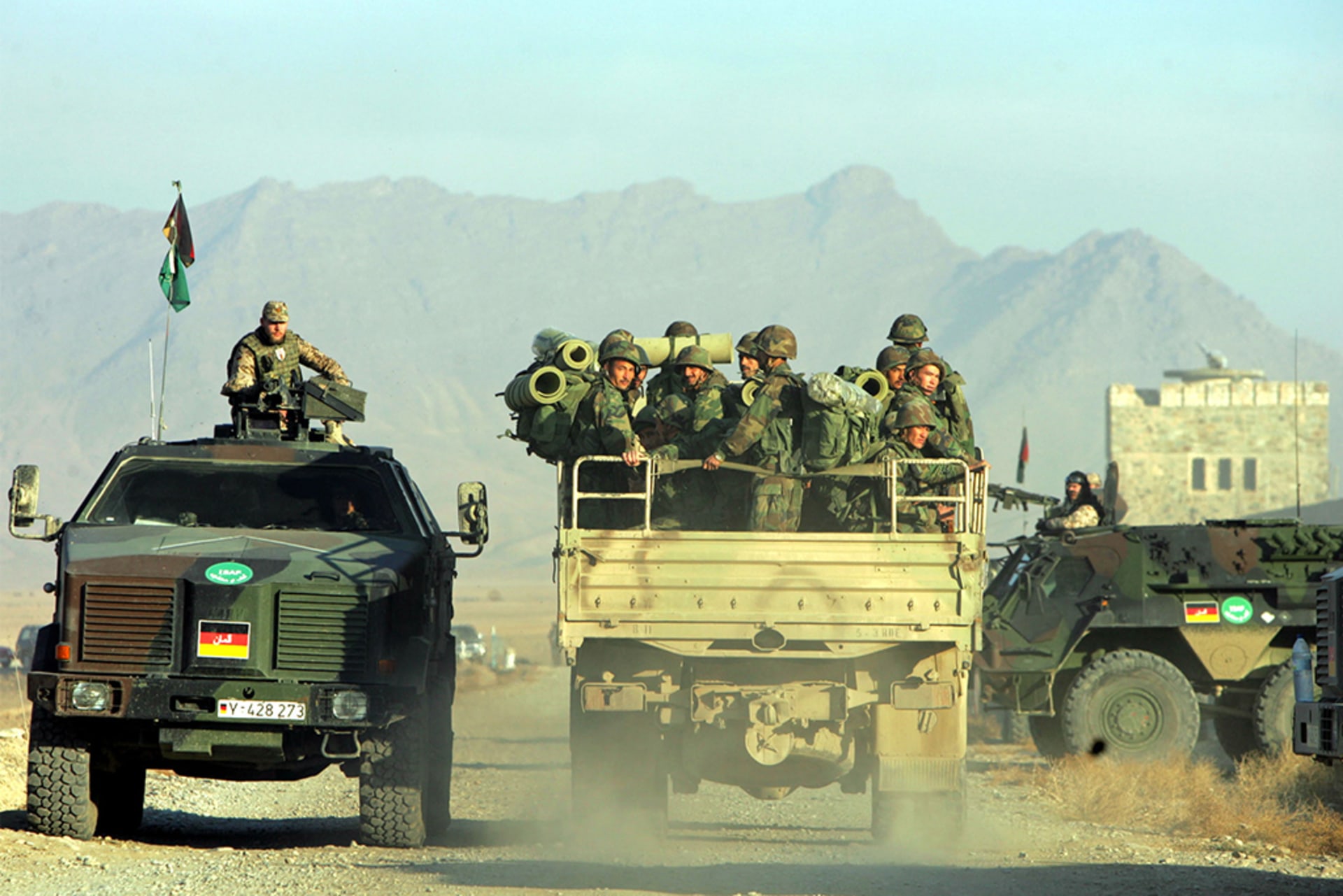 An Afghan army truck (right) drives beside a NATO-led International Security Assistance Force vehicle outside of Kabul on December 17, 2004.