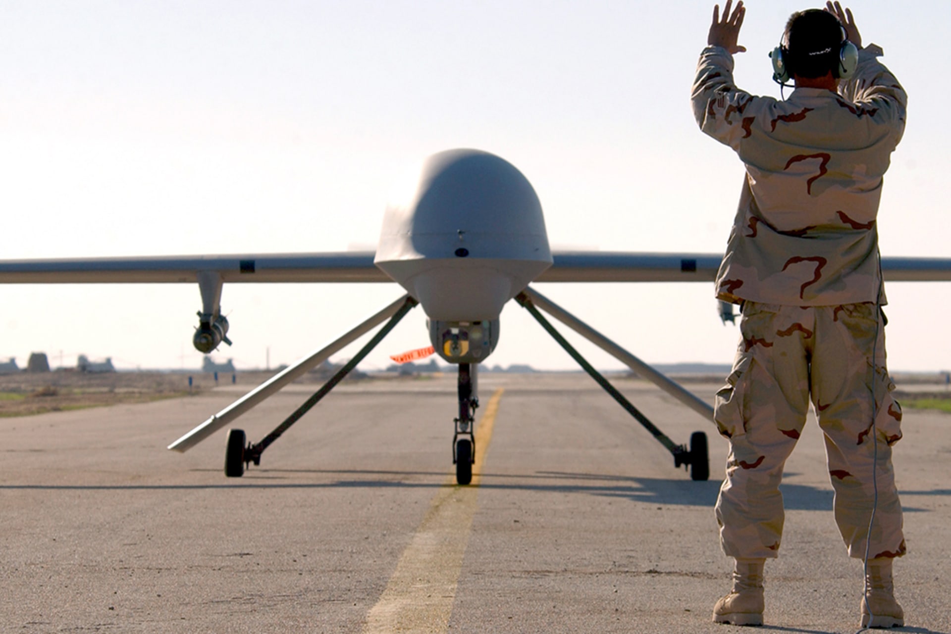 A U.S. Air Force airman marshals an RQ-1 Predator aircraft at the Tallil Air Base in Iraq, on January 20, 2004.