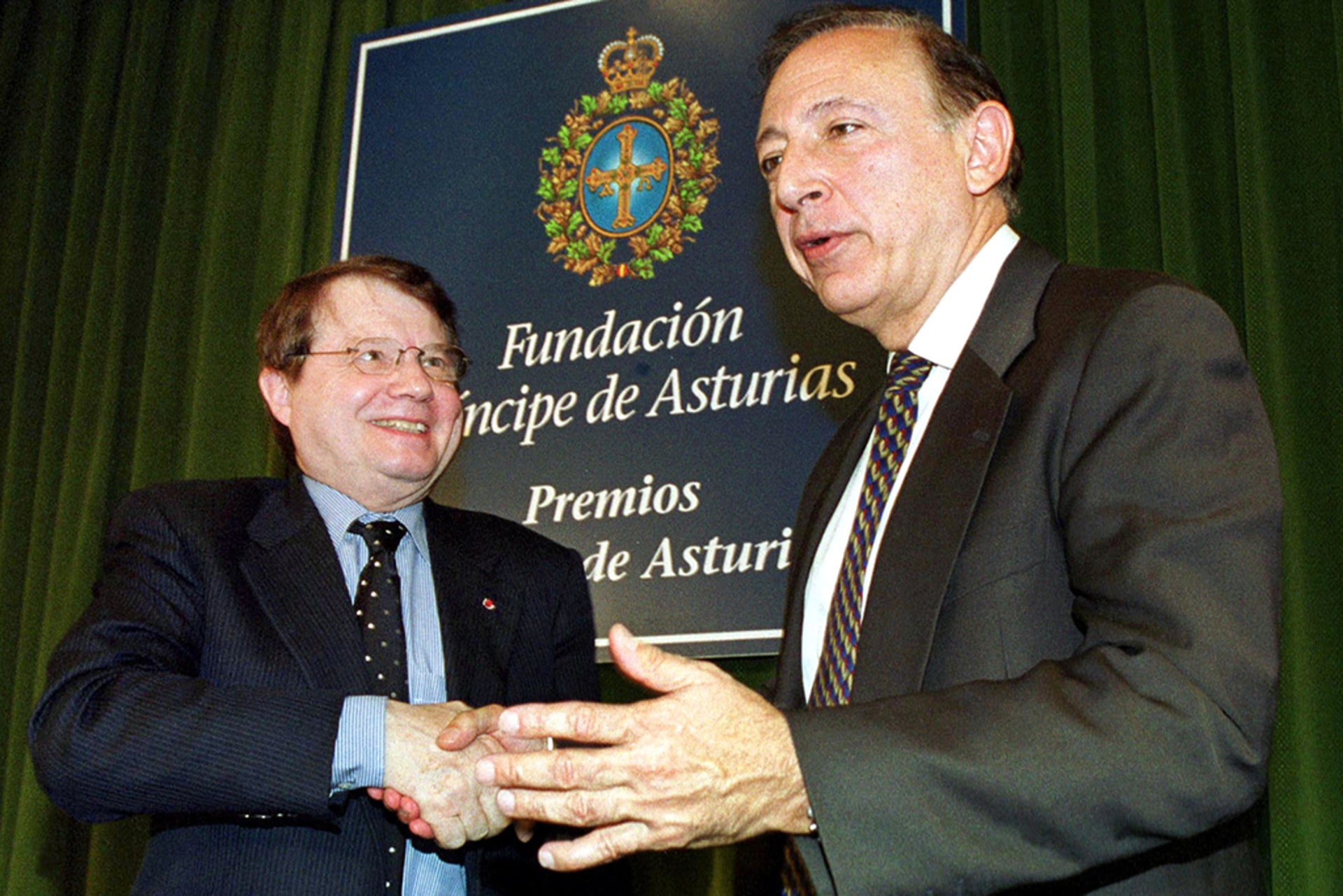 From left, scientists Luc Montagnier and Robert Gallo shake hands after a news conference in Oviedo, Spain, on October 26, 2000.
