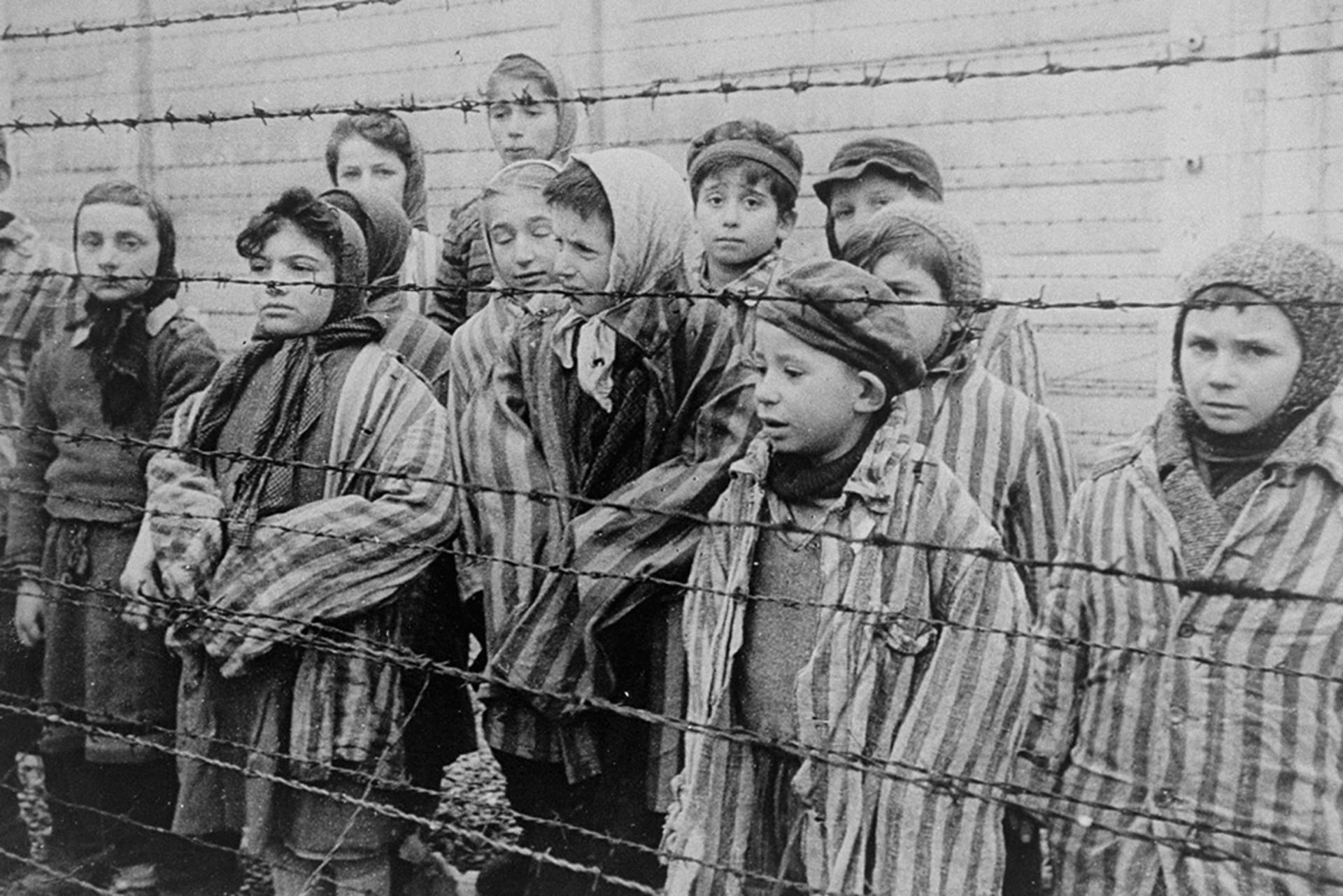 A group of child survivors behind a barbed wire fence at the Nazi concentration camp at Auschwitz-Birkenau in southern Poland.