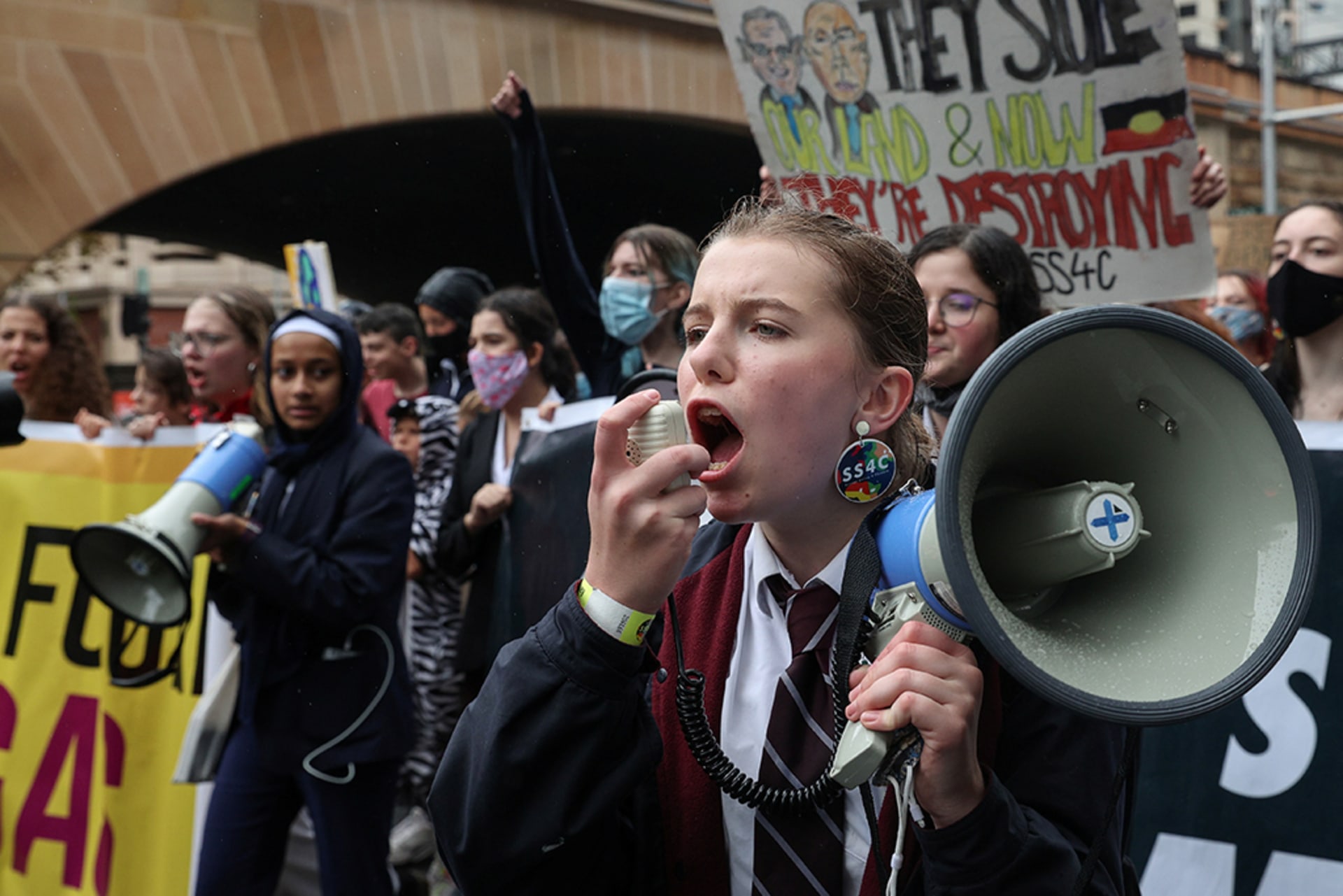 Students march during a "School Strike 4 Climate" rally, demanding action on climate change, in Sydney, Australia, May 21, 2021. A student shouts into a megaphone as other students hold signs.