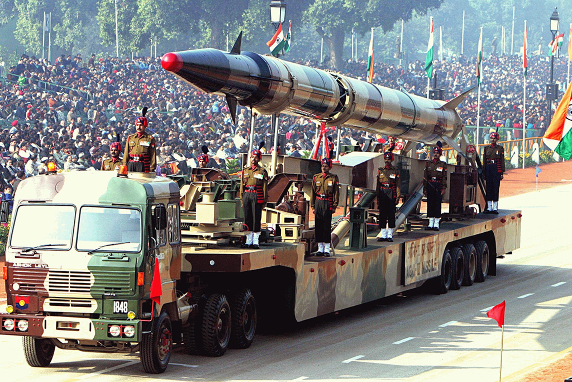 An intermediate range ballistic missile on a launcher during a parade in New Delhi. A massive crowd has amassed to watch.
