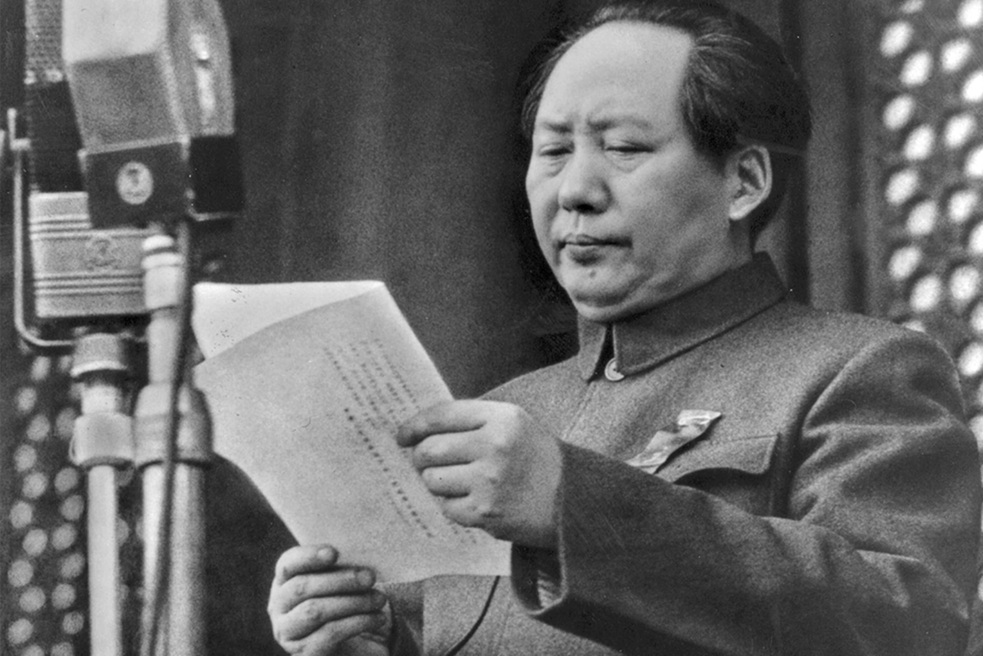 Mao Zedong reads a piece of paper in front of a microphone as he proclaims the founding of the People's Republic of China.