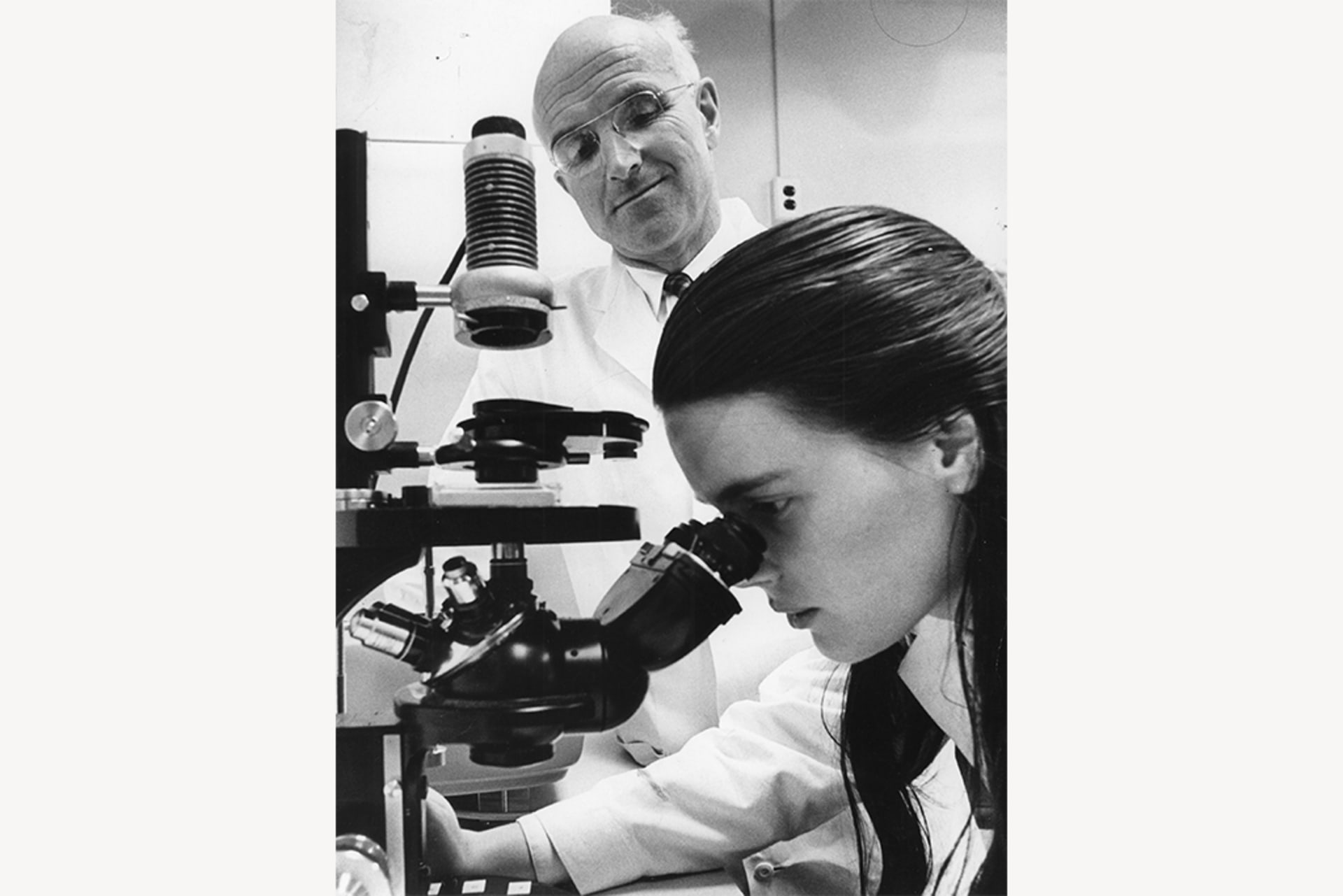 Dr. Joseph E. Murray looks on as a lab tech looks through a microscope, searching for good matches for kidney transplants, at Peter Bent Brigham Hospital in Boston.