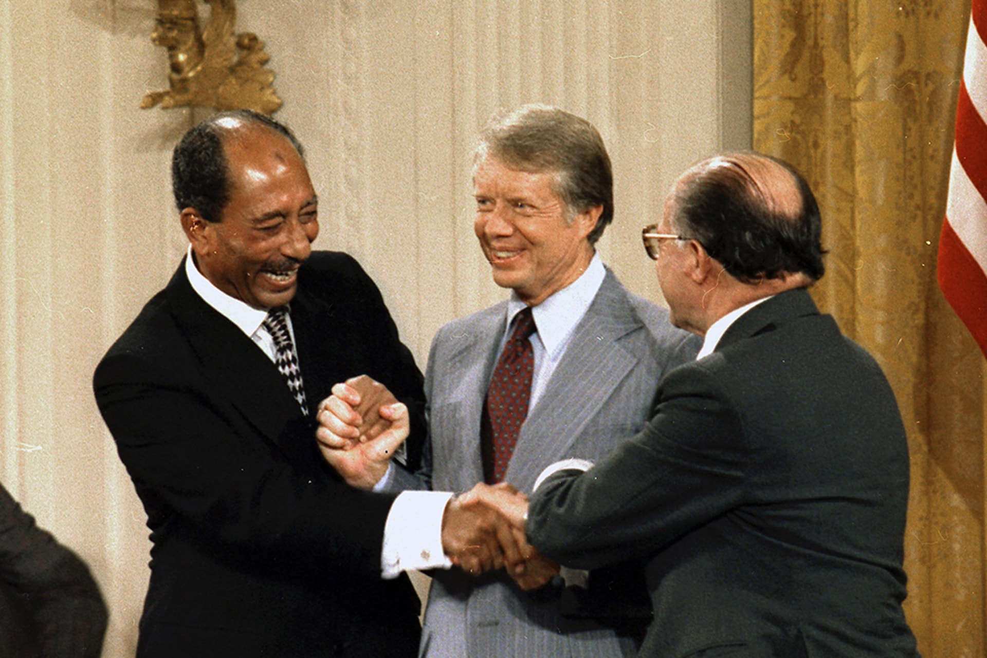 Anwar Sadat, Jimmy Carter, and Menachem Begin hold hands at the Camp David Accords signing ceremony.