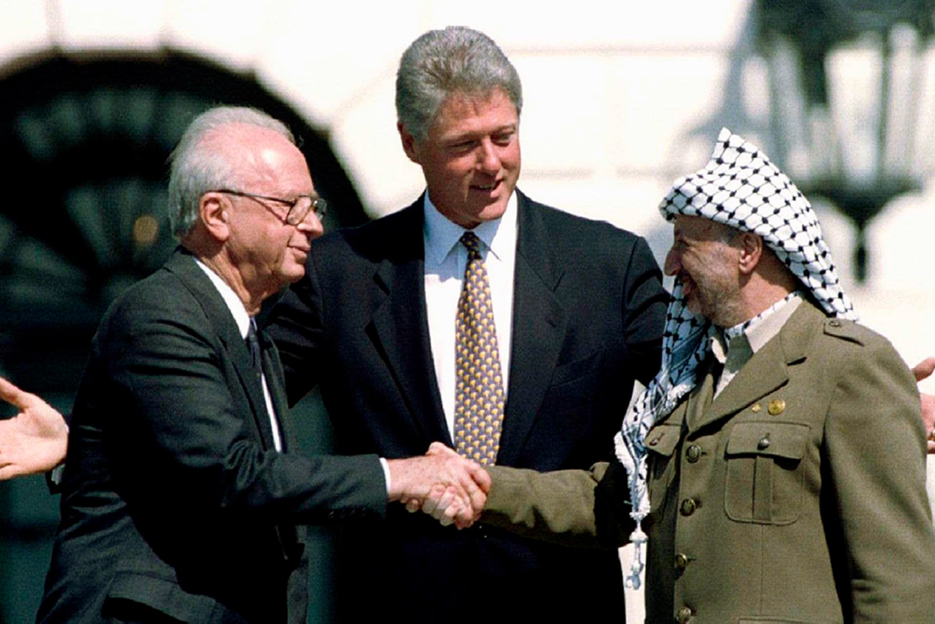 Palestine Liberation Organization Chairman Yasser Arafat (R) shake hands with Israeli Prime Minister Yitzhak Rabin (L), as U.S. President Bill Clinton stands between them, after signing the Oslo Accord, in Washington, D.C.